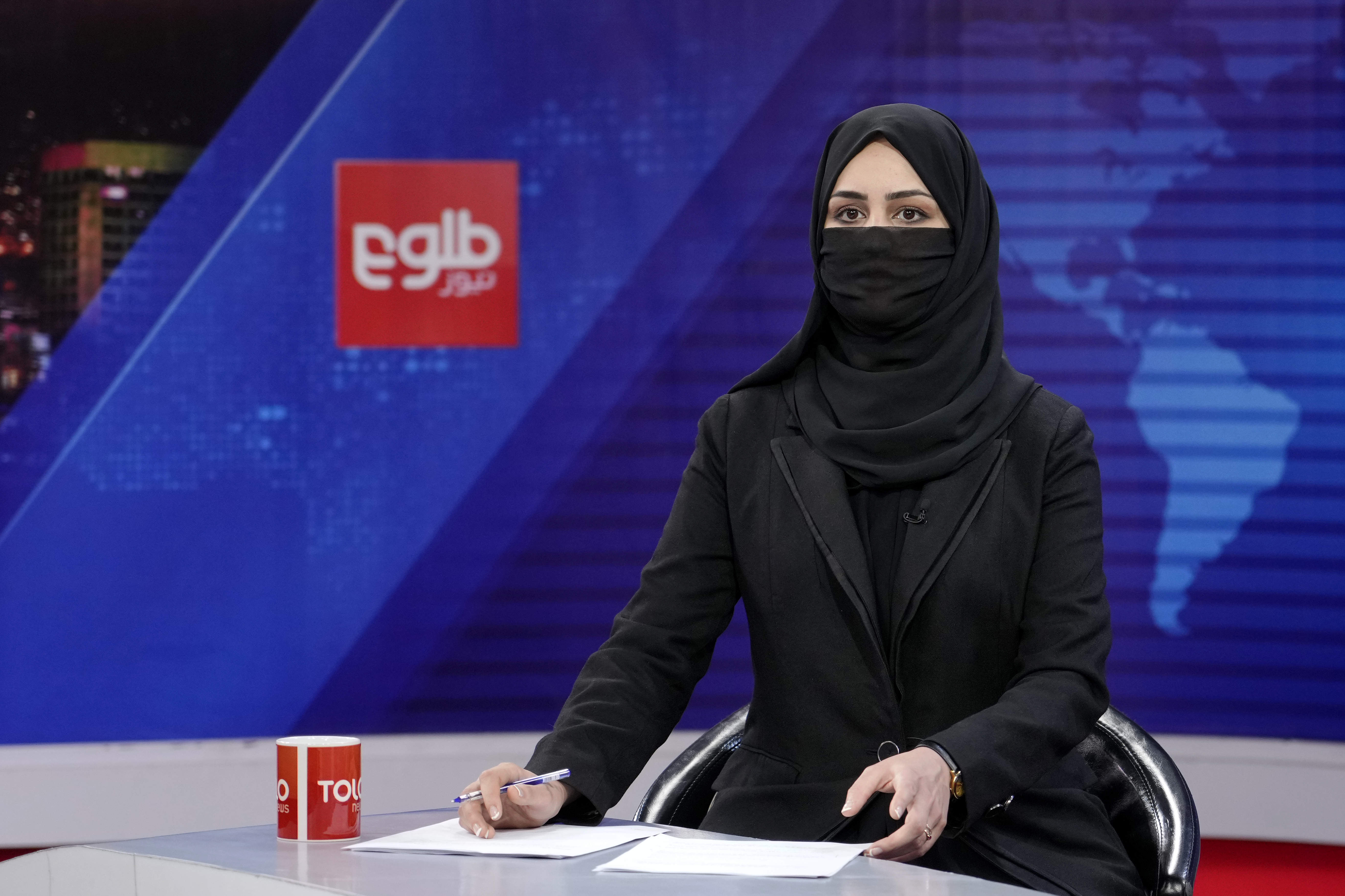 Khatereh Ahmadi a TV anchor wears a face covering as she reads the news on TOLO NEWS, in Kabul, Afghanistan, Sunday, May 22, 2022. Afghanistan's Taliban rulers have begun enforcing an order requiring all female TV news anchors in the country to cover their faces while on-air. The move Sunday is part of a hard-line shift drawing condemnation from rights activists.