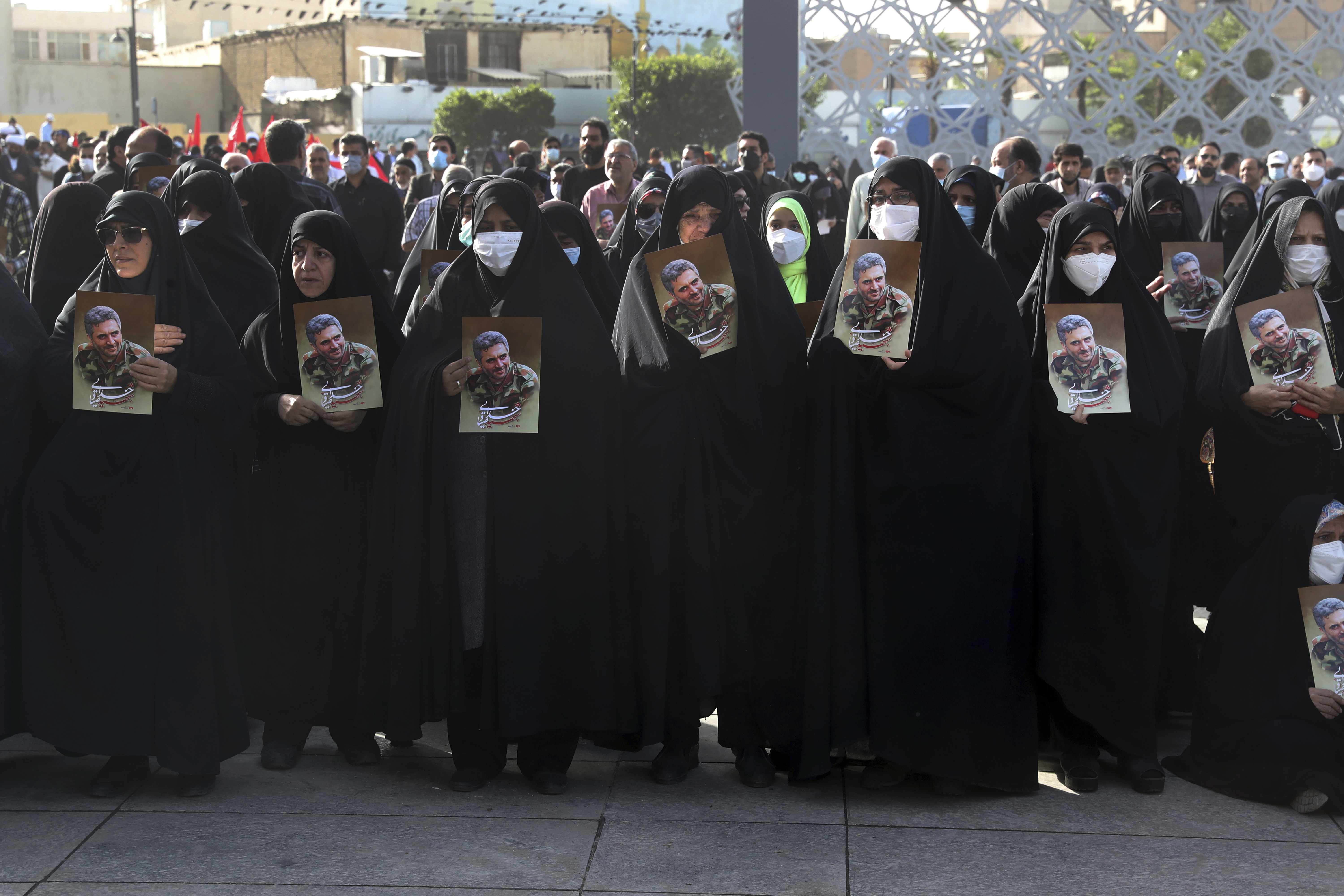 Mourners hold posters of Iran's Revolutionary Guard Col. Hassan Sayyad Khodaei during his funeral ceremony