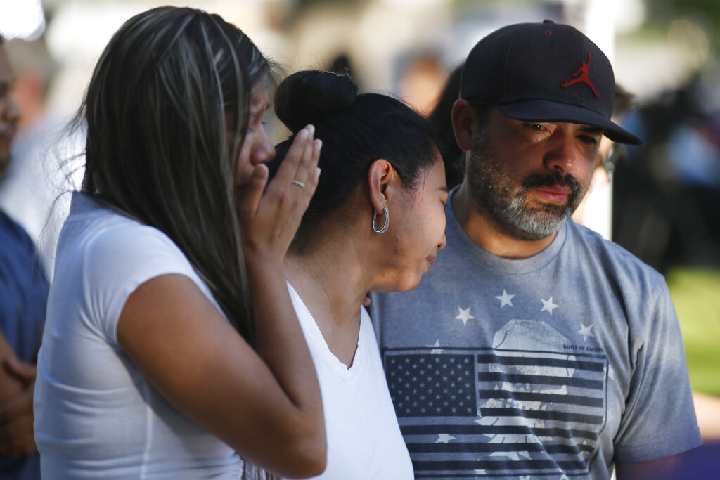 Mario Games, right, and his wife, Marisela and daughter Emily, react as they stand in front of a cross with the name of their niece, Nevaeh Bravo, at a memorial site for the victims killed in this week's elementary school shooting in Uvalde, Texas.