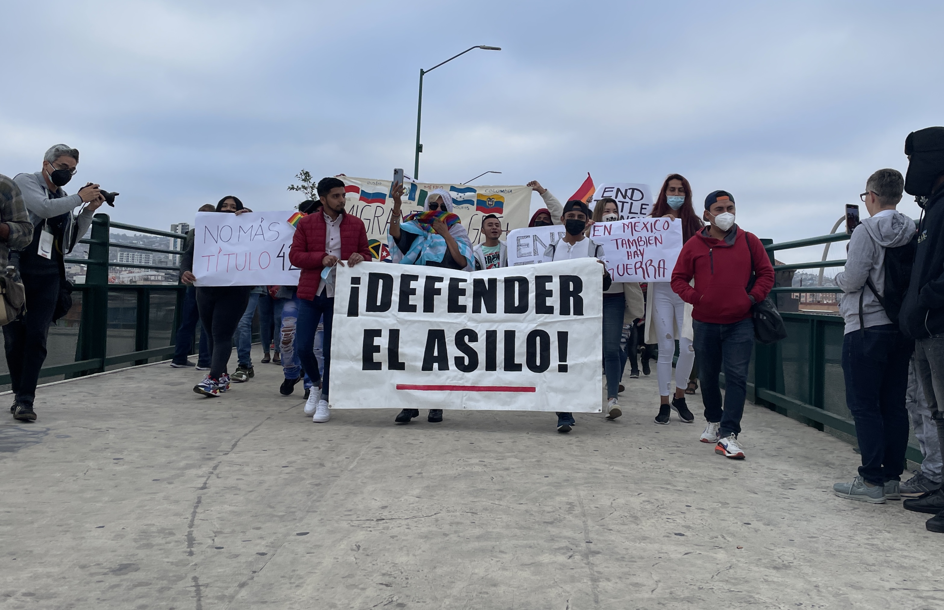 Refugees and migrants march across a bridge in Tijuana.