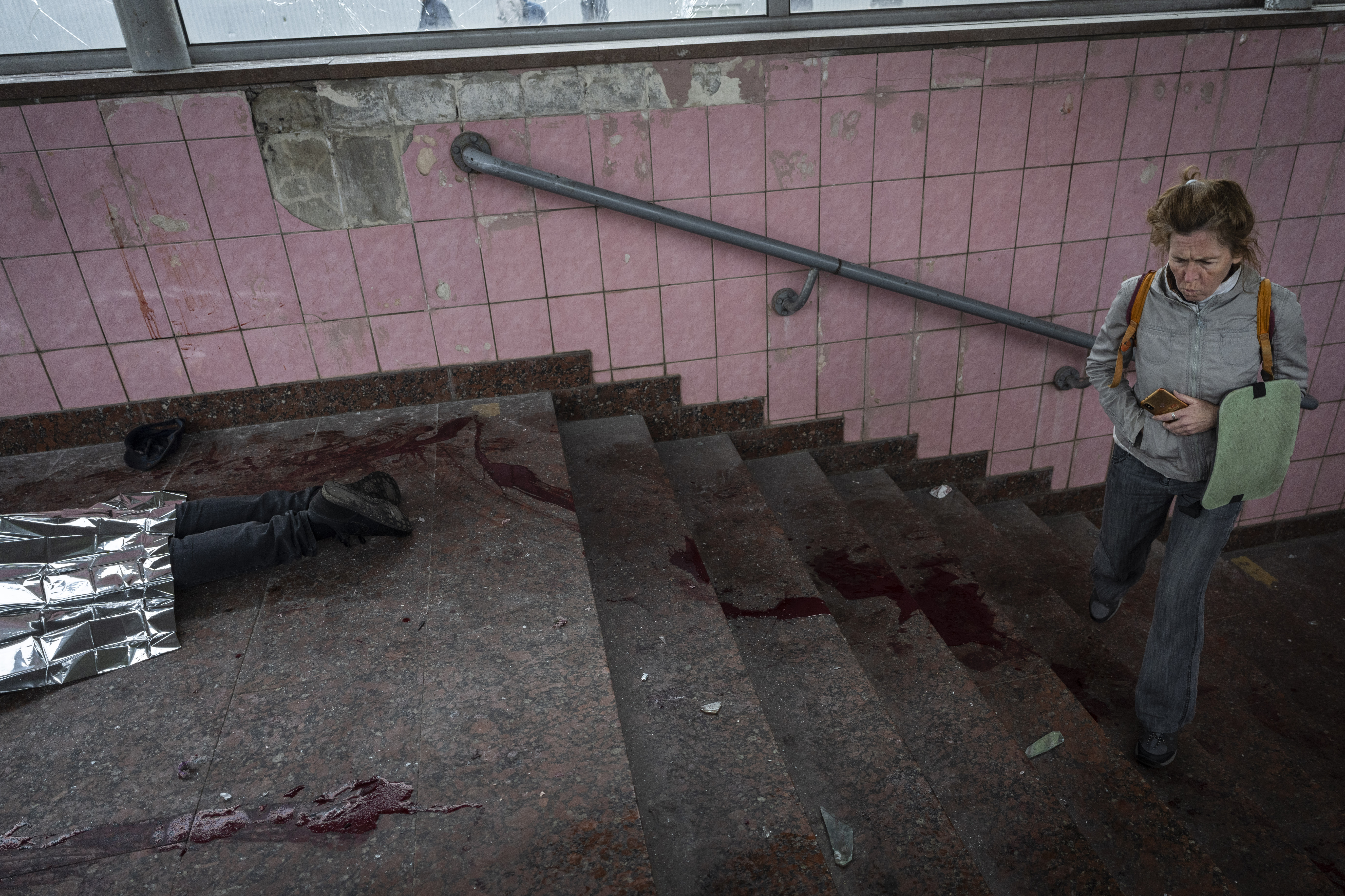 A woman walks next to the body of a man killed during shelling in Kharkiv, eastern Ukraine.