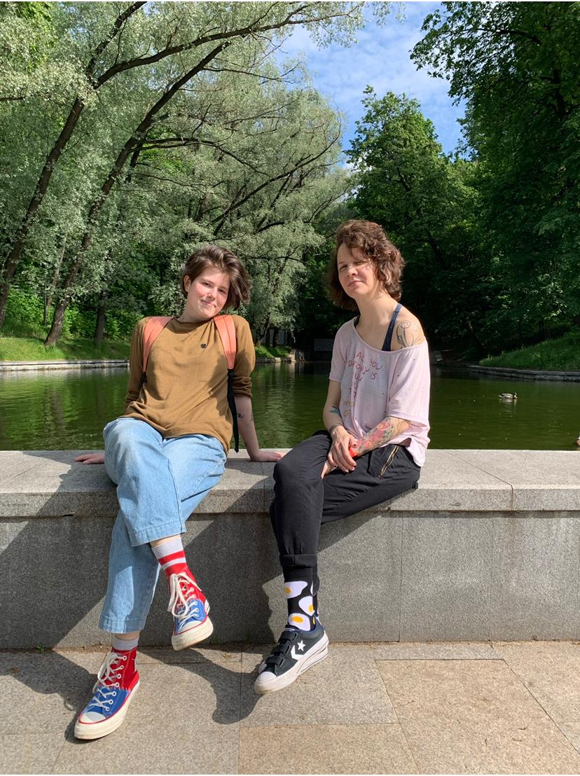 A photo of two women sitting side by side by a park lake.