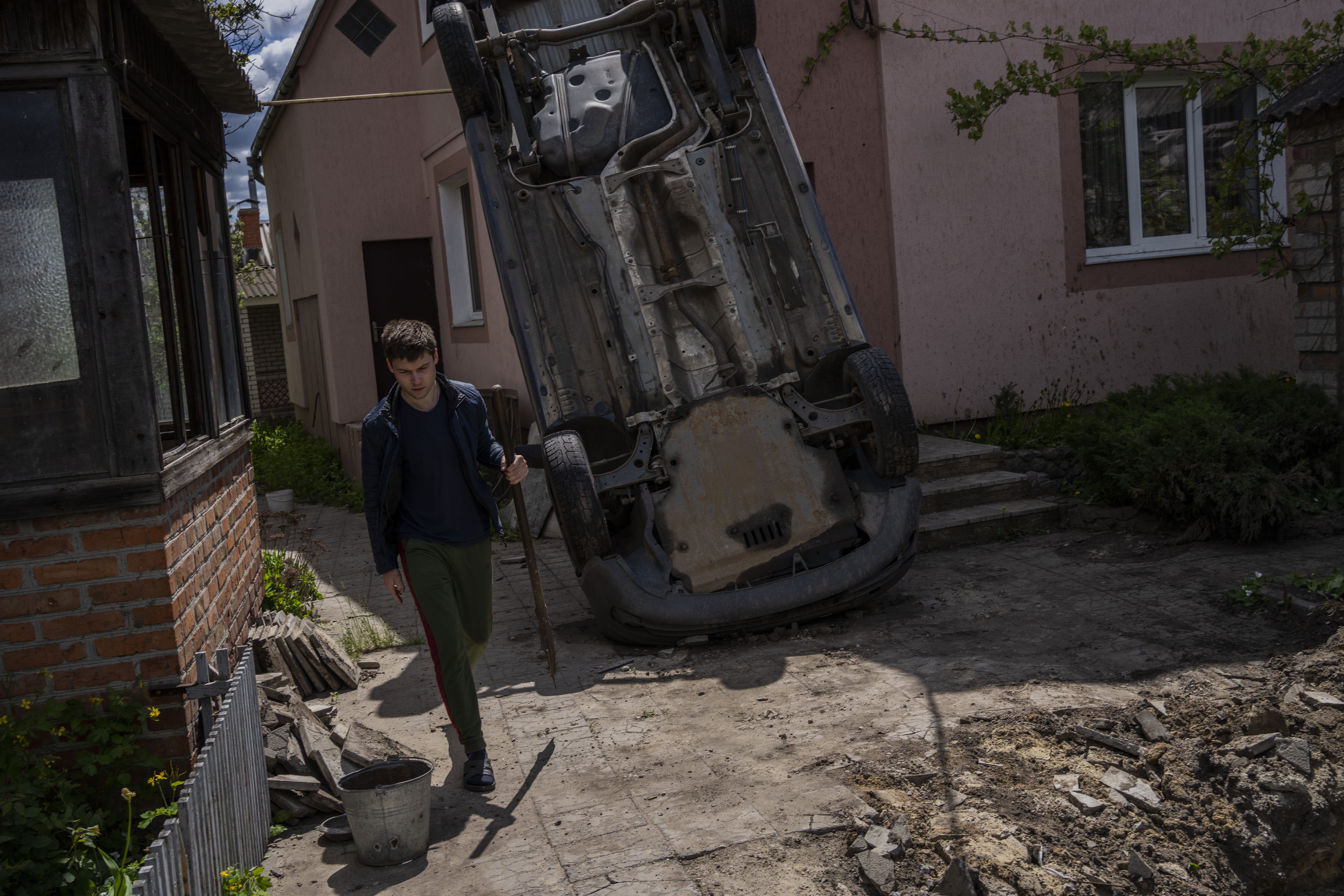 A resident carries a shovel to clear the rubble from his house damaged during a shelling in Kharkiv