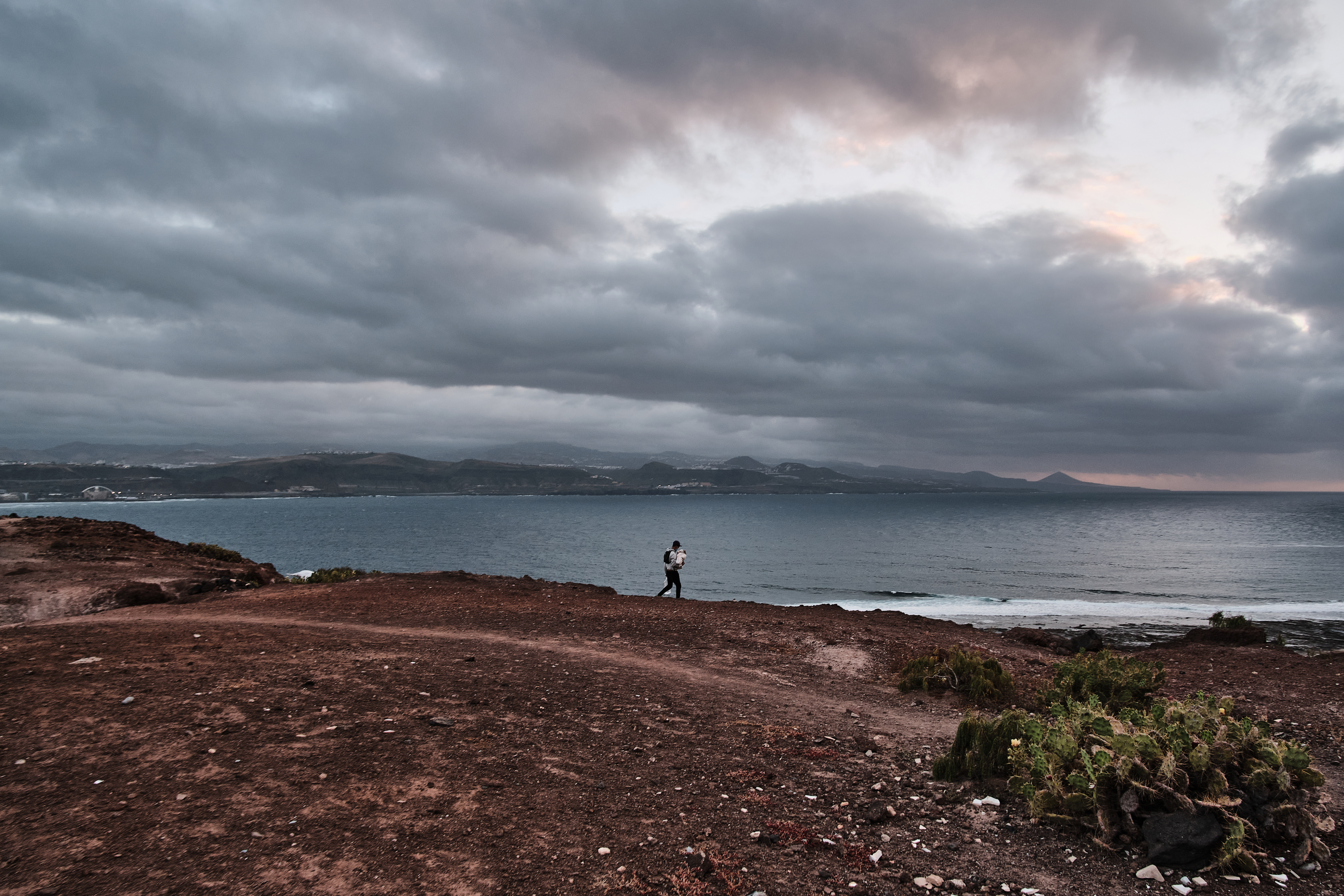 A photo of a man from Morocco carries food supplies to his tent settlement by the sea.