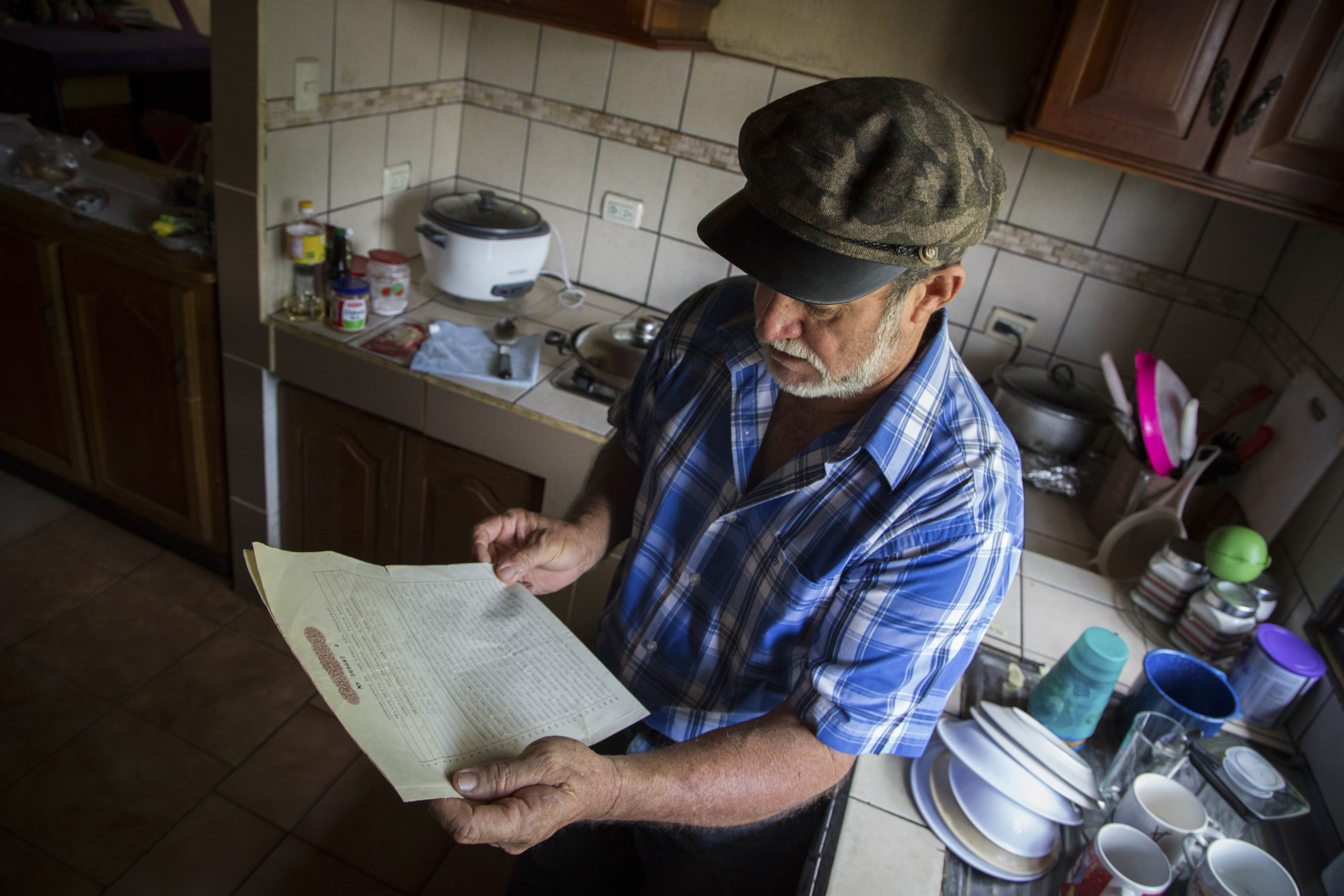A photo of William Vega, 60, in his kitchen, holding the deed to the 100-hectare (247-acre) farm.