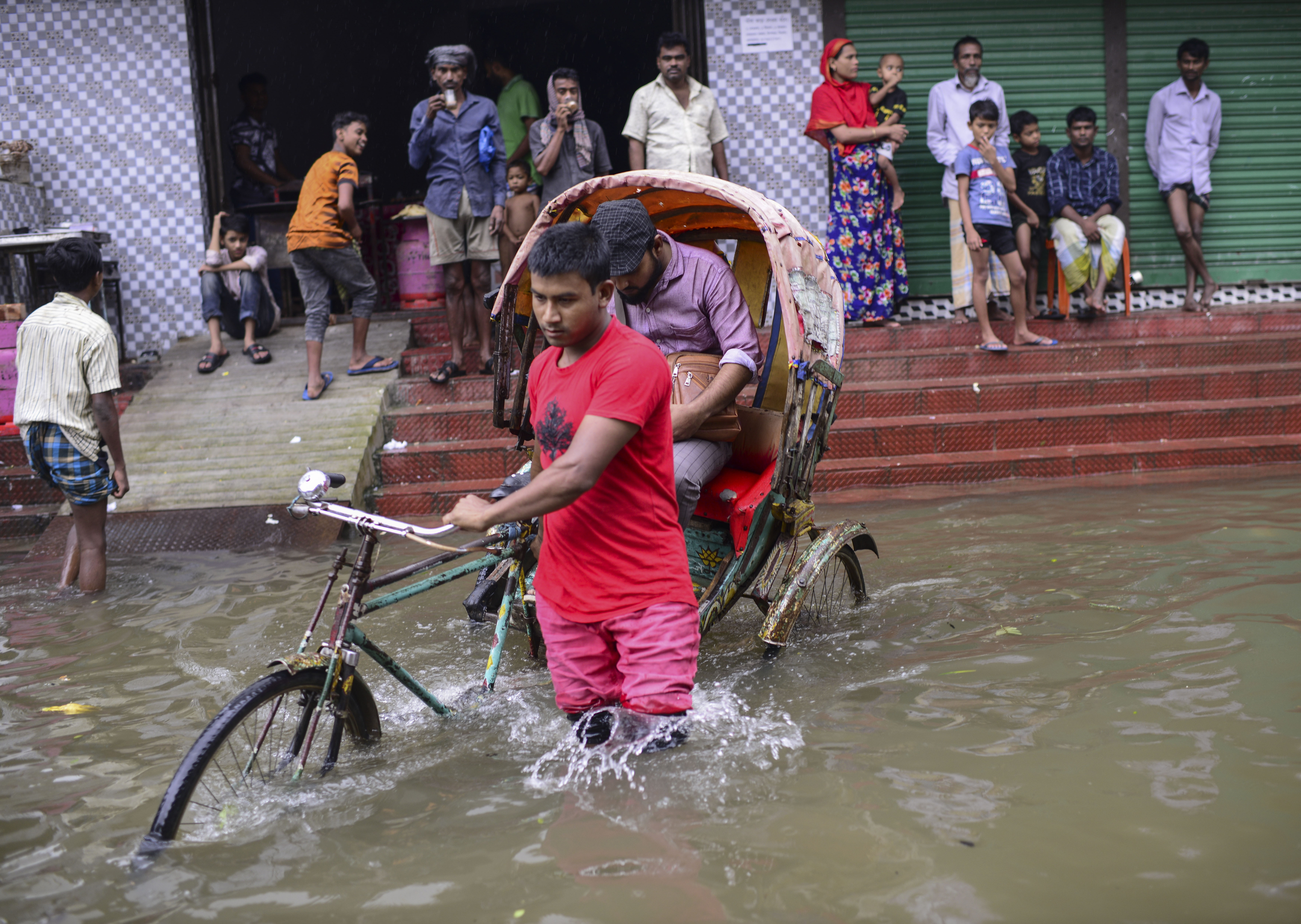 A rickshaw puller wades through flood waters in Sylhet
