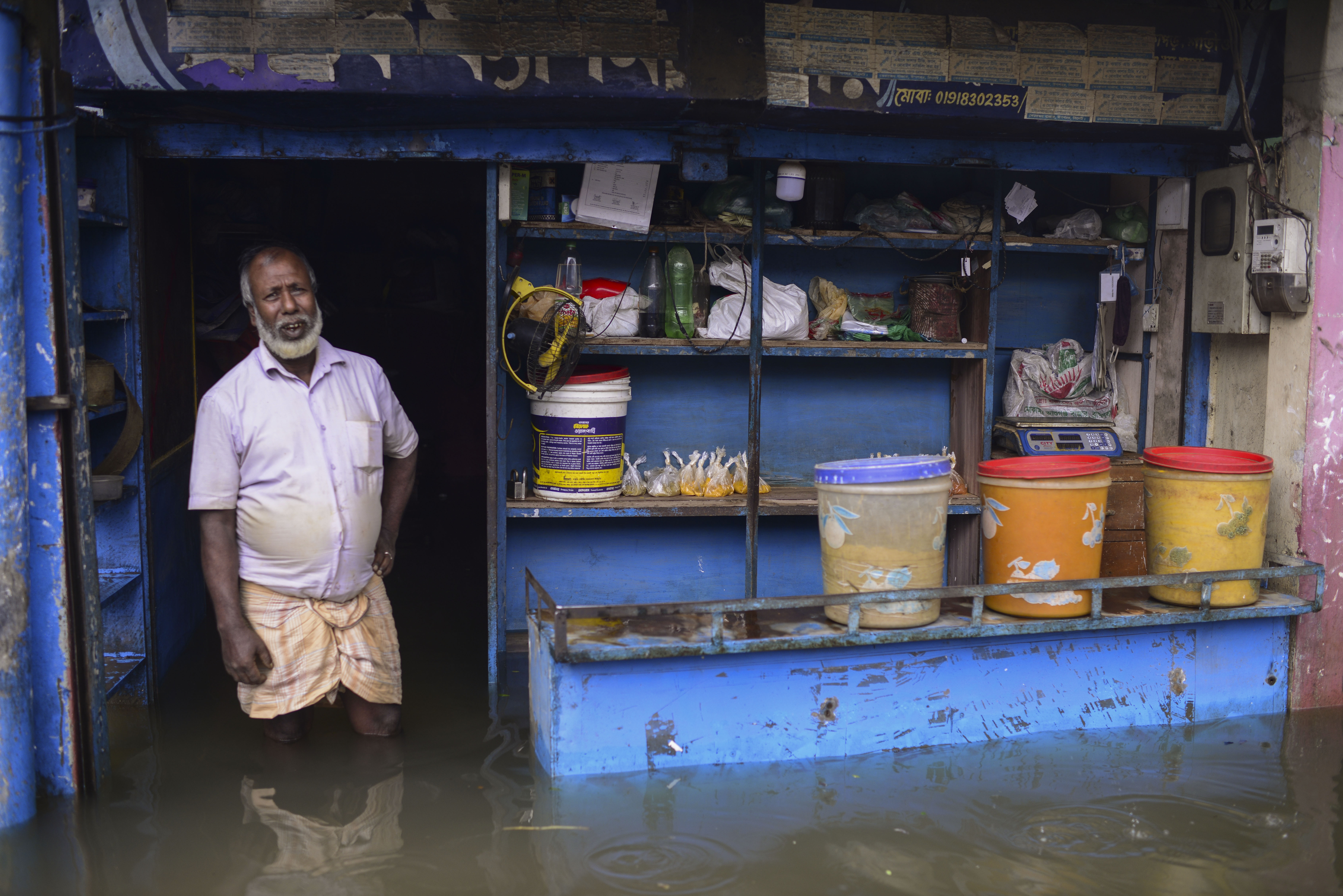 A man stands at the doorway of his flooded shop in Sylhet