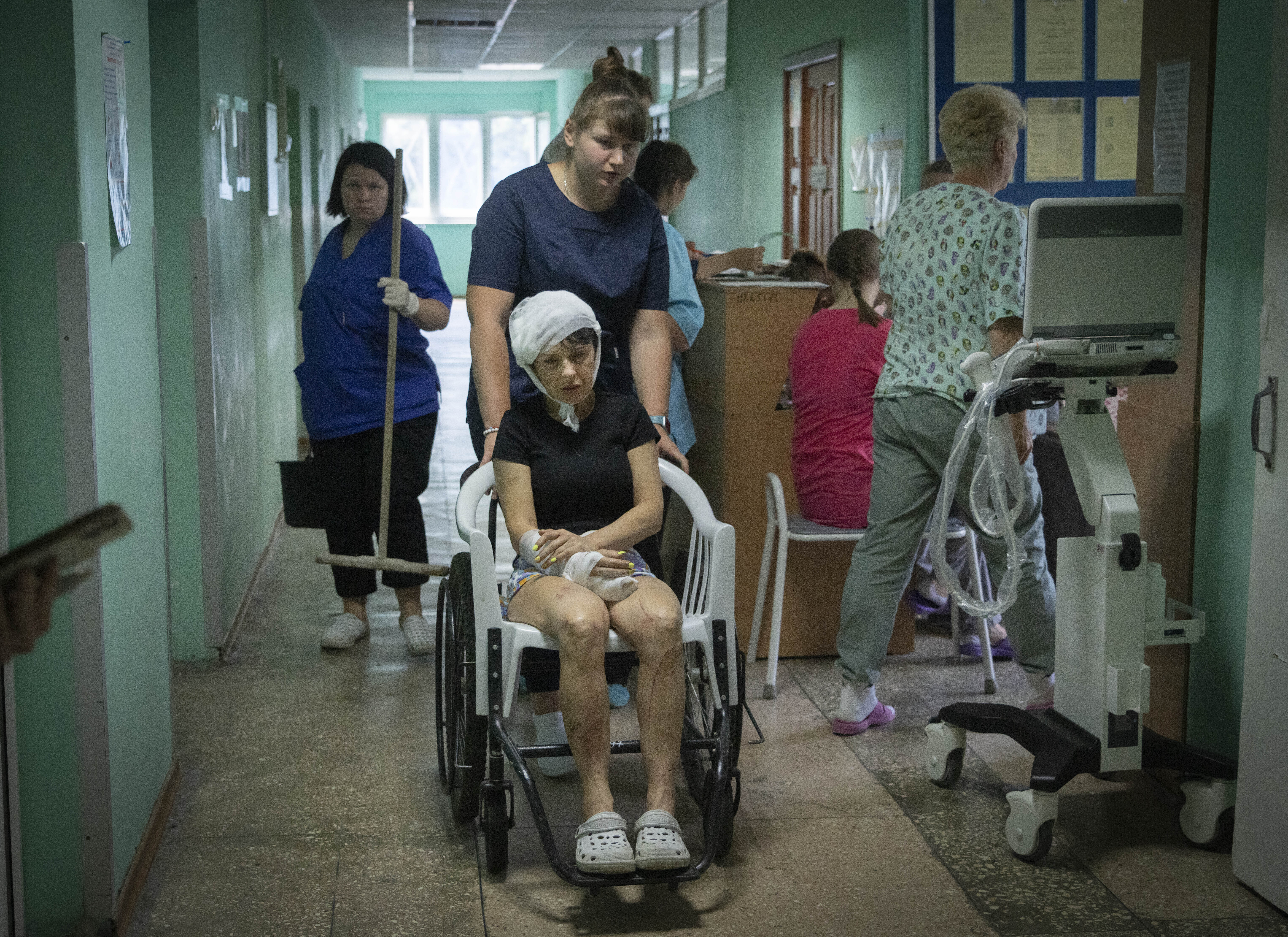 A hospital nurse pushes a wheelchair carrying a woman wounded by the Russian rocket attack at a shopping centre in a city hospital in Kremenchuk