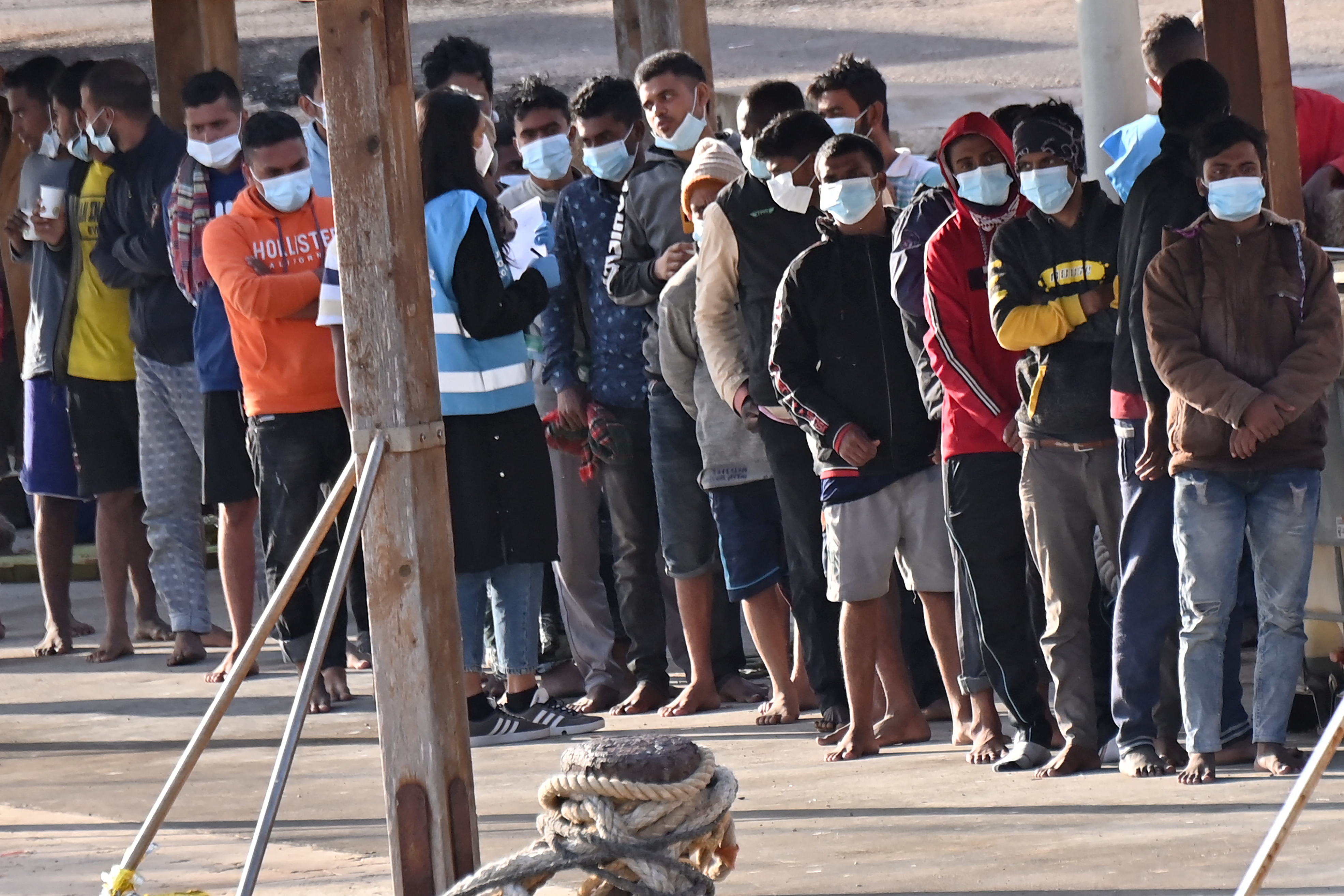Migrants line up after disembarking on the southern Italian Pelagie Island of Lampedusa on May 17, 2021.