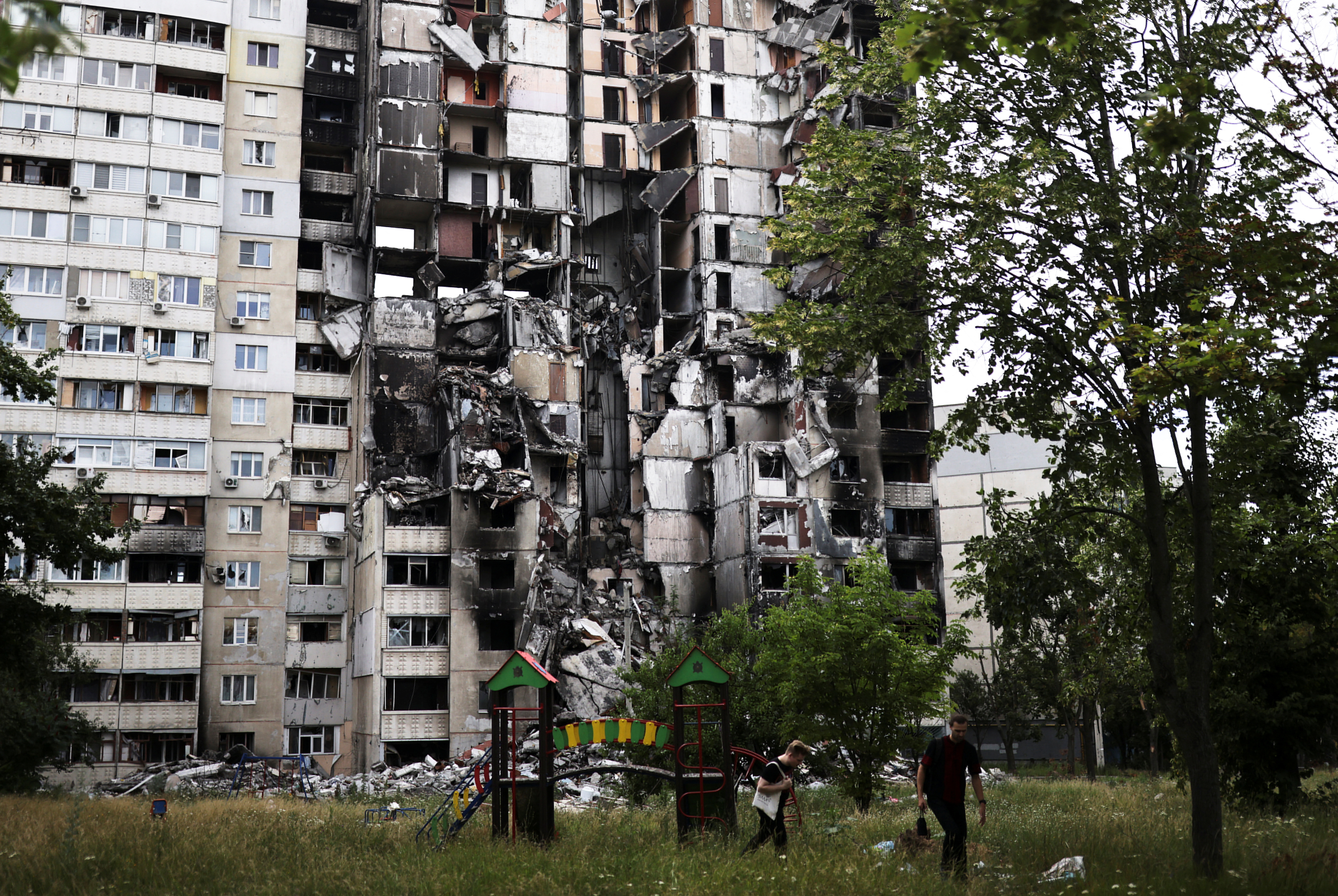 Neighbours walk next to a building destroyed by a military raid as Russia's invasion of Ukraine continues, in northern Saltivka, in the region of Kharkiv, Ukraine.
