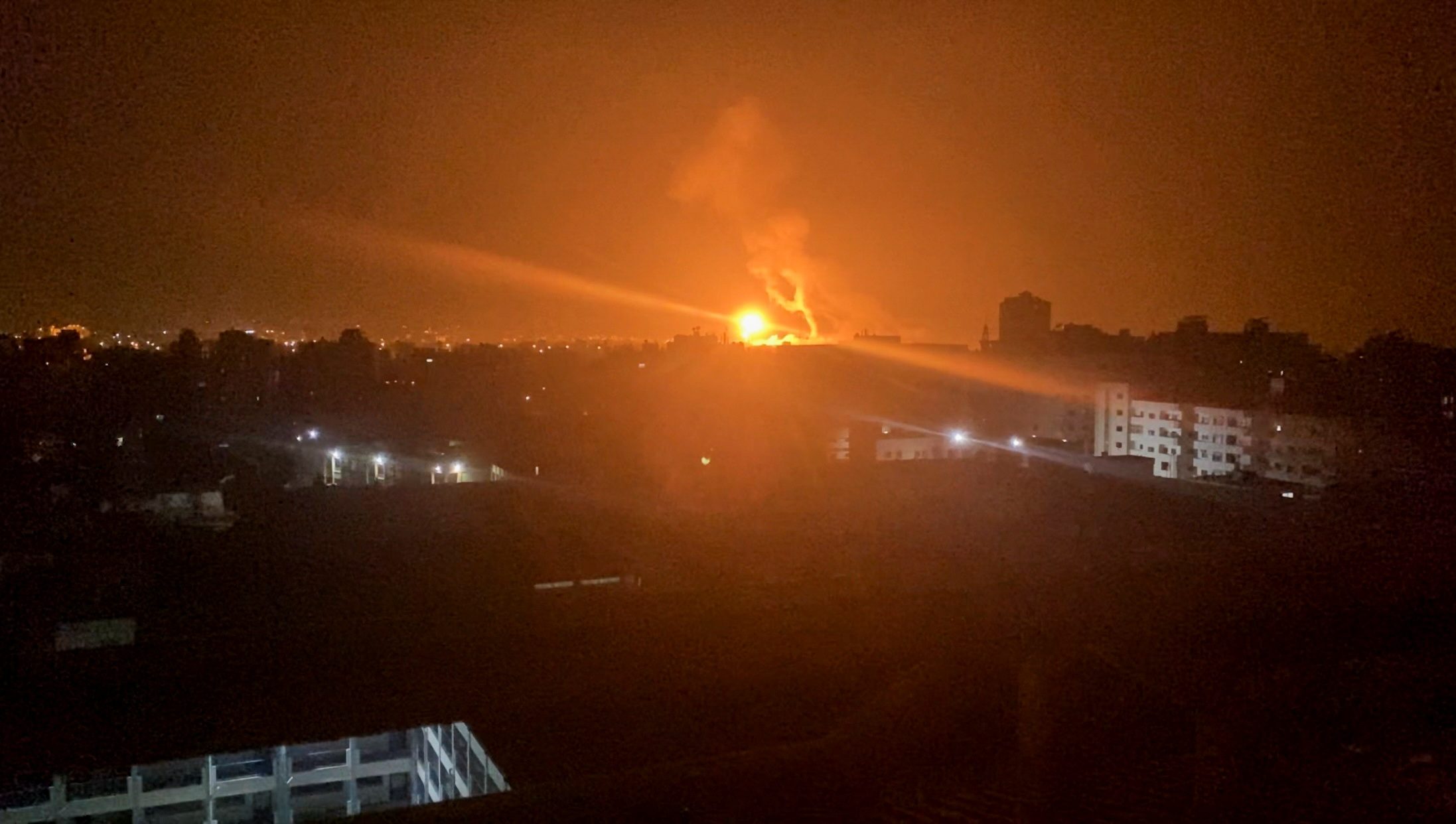 An explosion from an Israeli air raid on Gaza illuminates some buildings at night