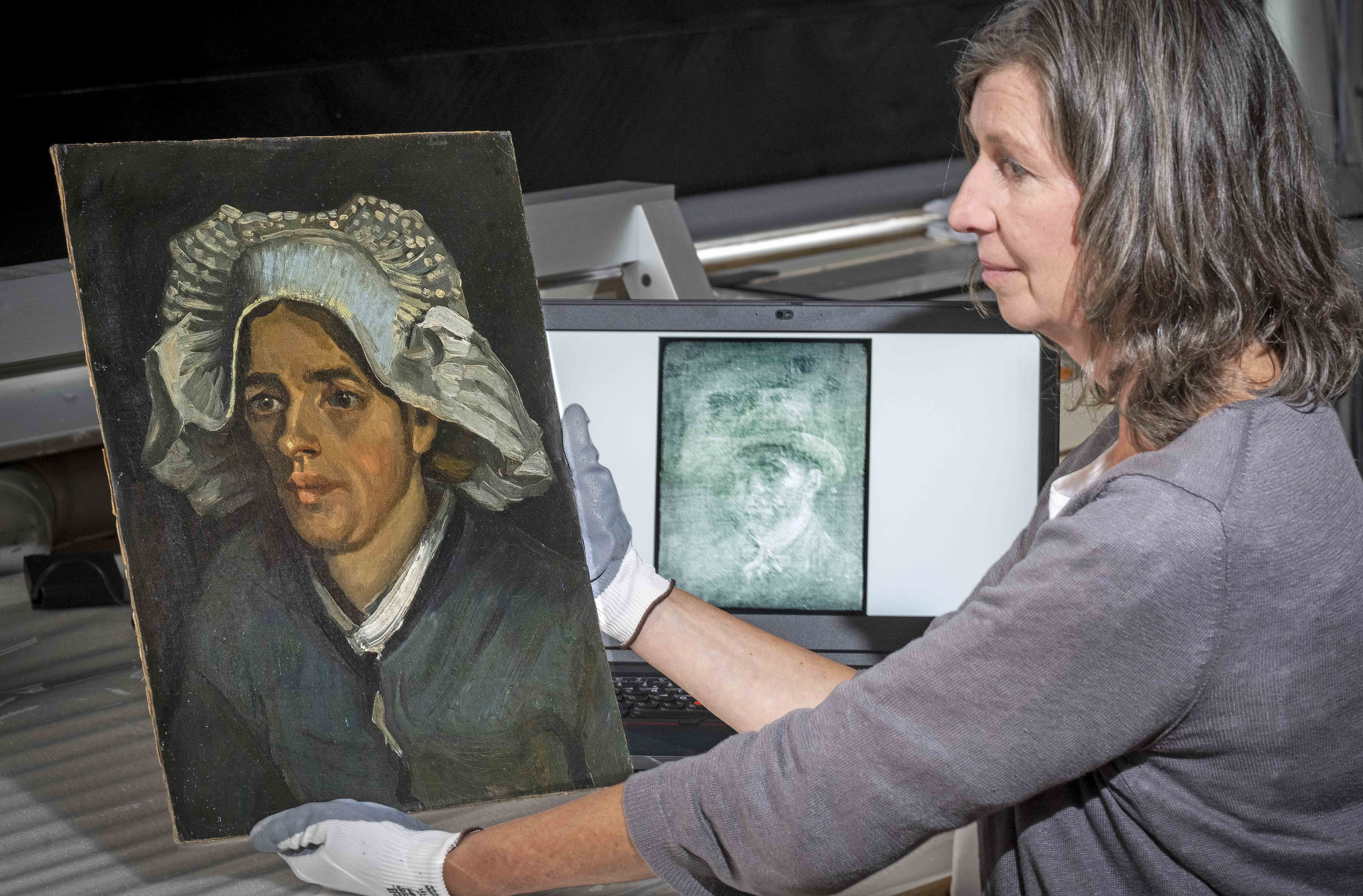 A painting conservator looks at the image behind the canvas through a an X-ray image through a specially designed lightbox.