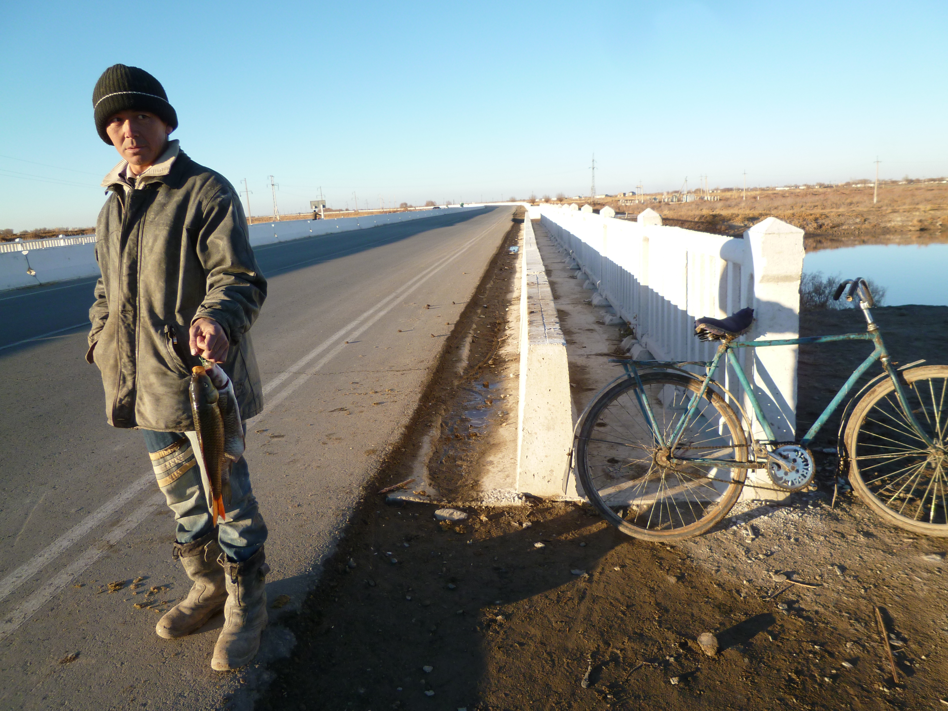 A Karakalpak fisherman standing near a bridge
