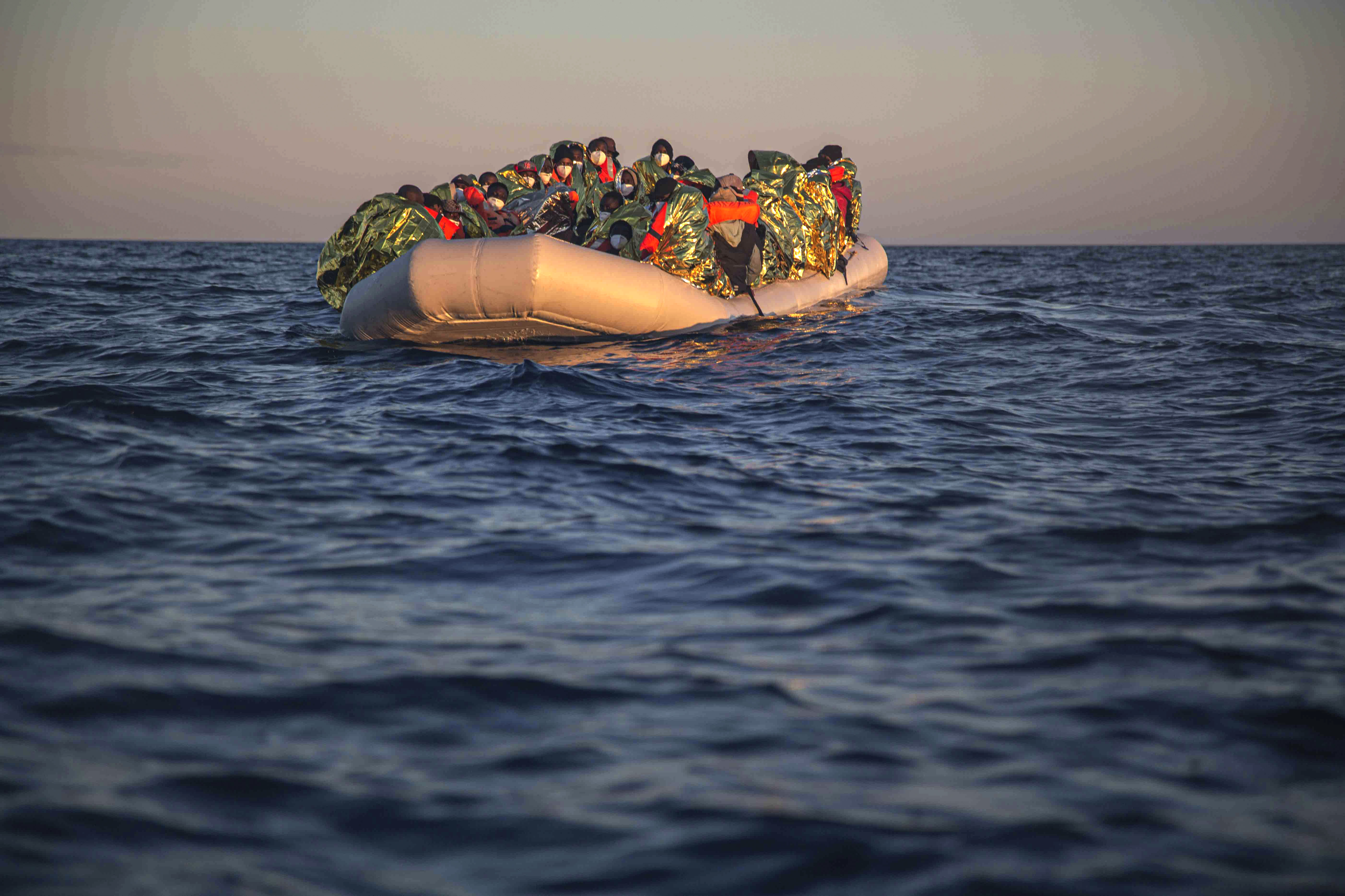 Migrants and refugees from different African nationalities wait on an overcrowded rubber boat, as aid workers of the Spanish NGO Open Arms approach them in the Mediterranean Sea, international waters, off the Libyan coast, Saturday, Feb. 6, 2021. (AP Photo/Pablo Tosco)