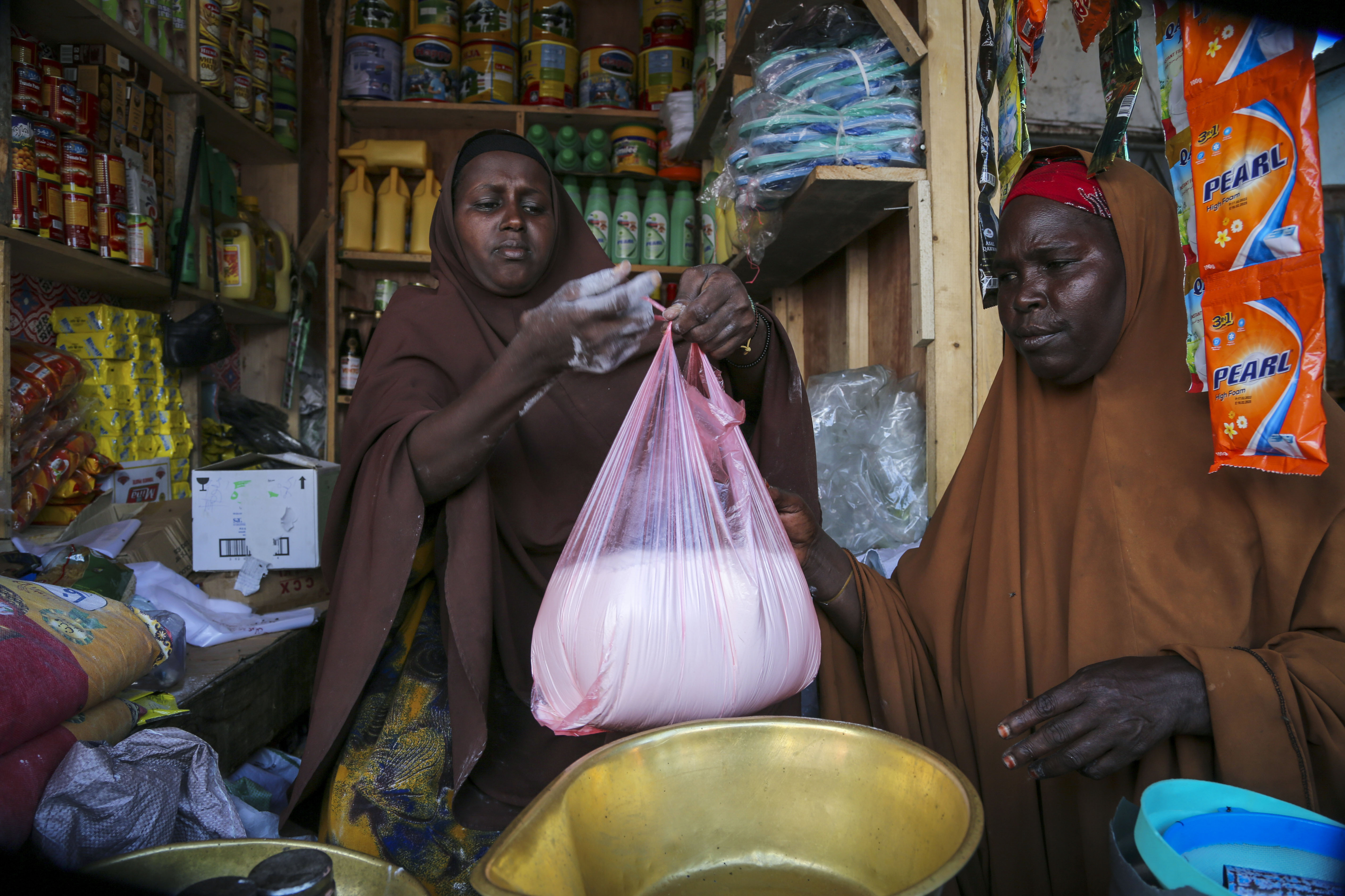 FILE - Halimo Hersi, 42, right, buys wheat flour from a shopkeeper in the Hamar-Weyne market in the capital Mogadishu, Somalia Thursday, May 26, 2022. Russian hostilities in Ukraine are preventing grain from leaving the “breadbasket of the world" and making food more expensive across the globe, raising the specter of shortages, hunger and political instability in developing countries. Together, Russia and Ukraine export nearly a third of the world’s wheat and barley, more than half its sunflower oil and are big suppliers of corn.