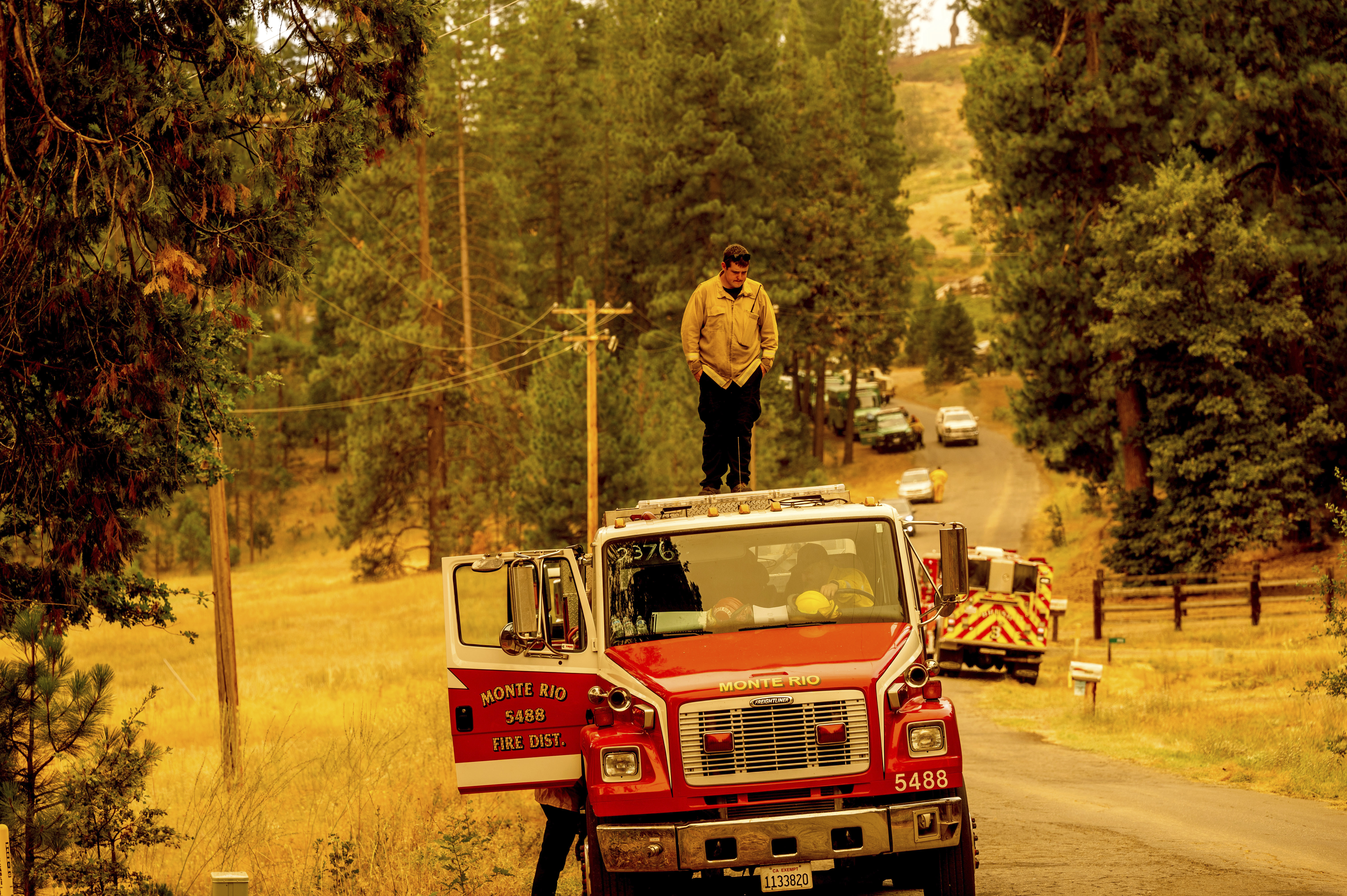 A US firefighter stands on top of a fire engine as crews battle the Oak Fire in California.