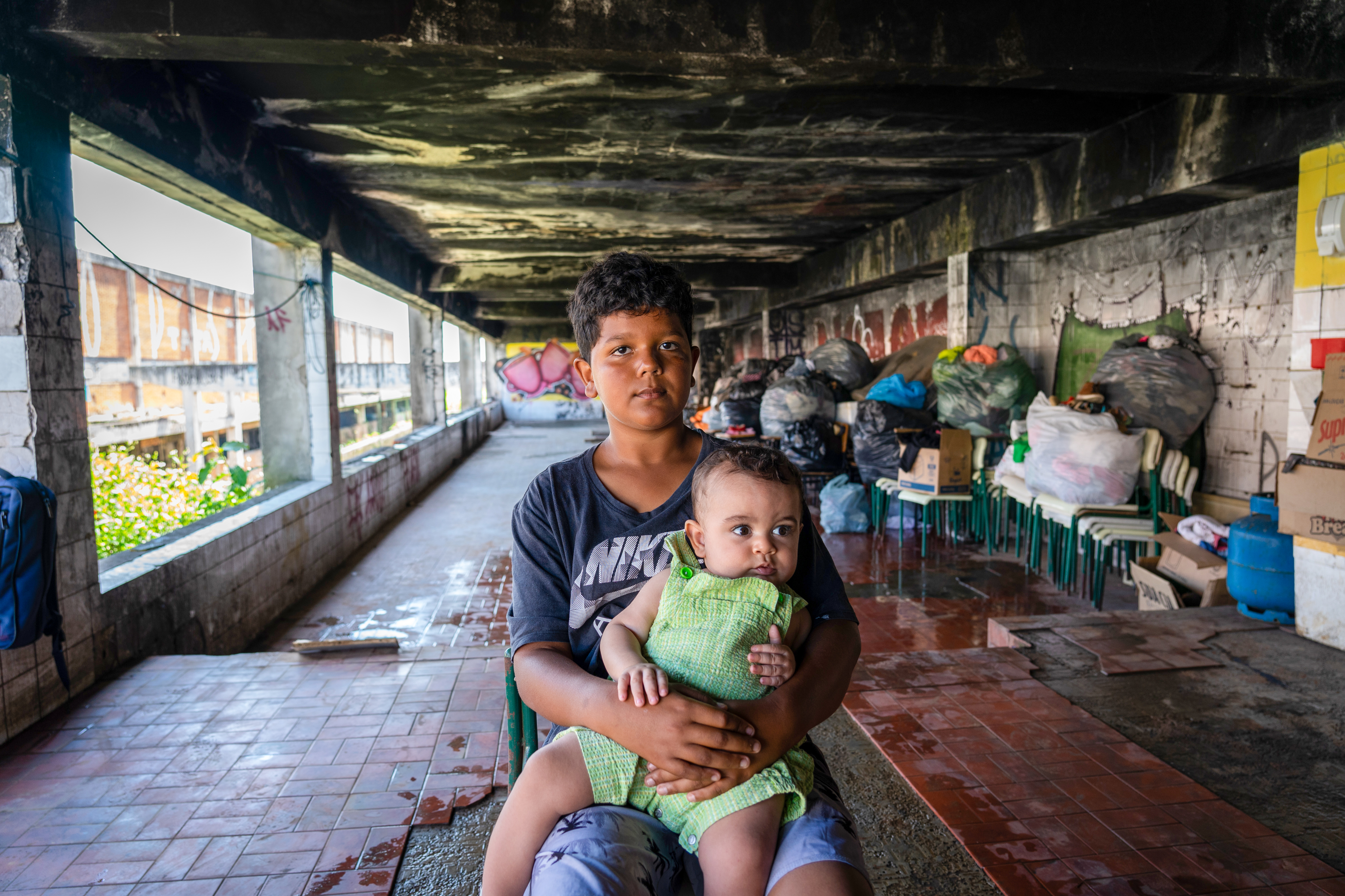 Joao Vitor, 8, holds his baby brother. Despite suffering bullying at school he is proud of his new home.