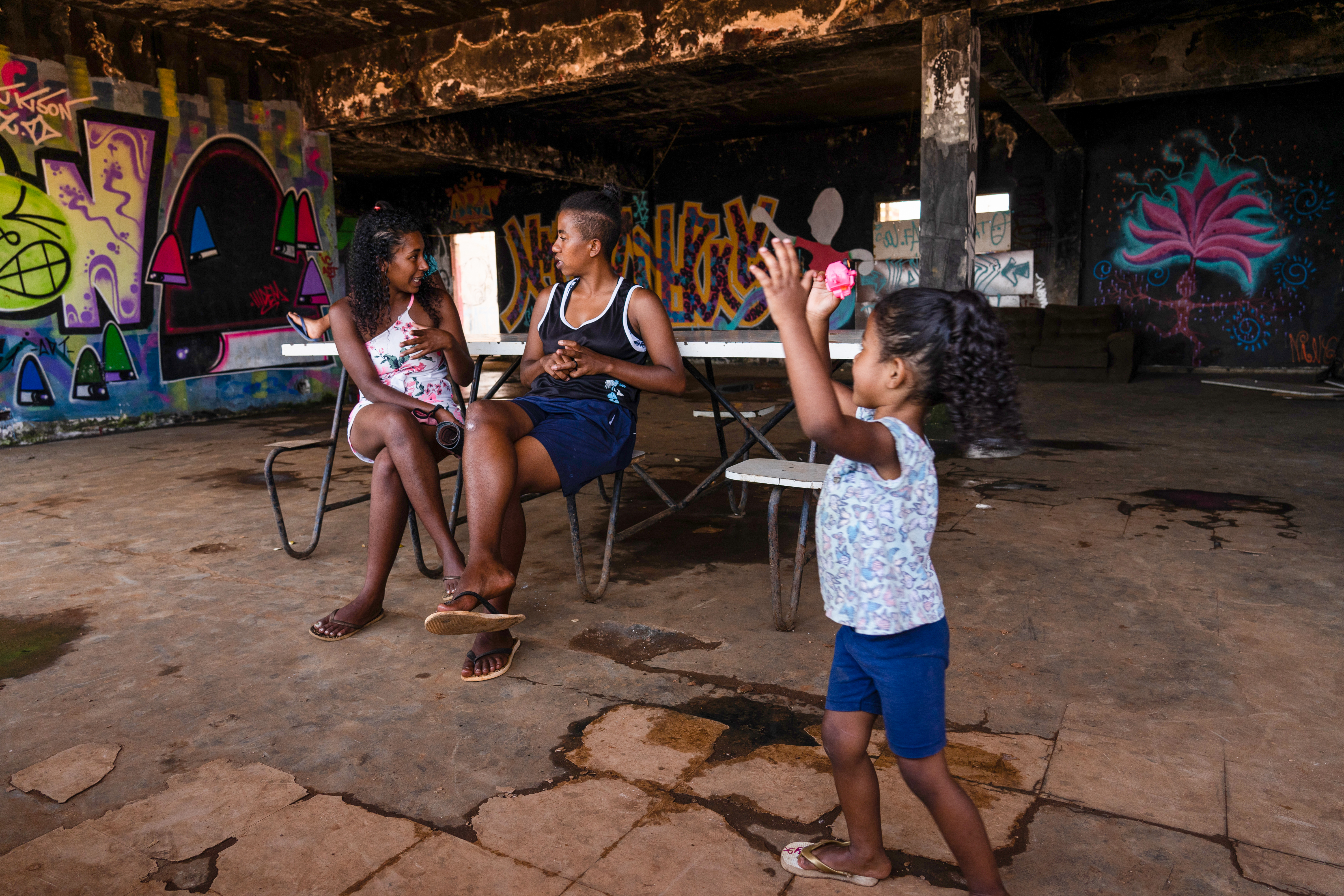 A child plays in front of her mother. Most residents here are single mothers.