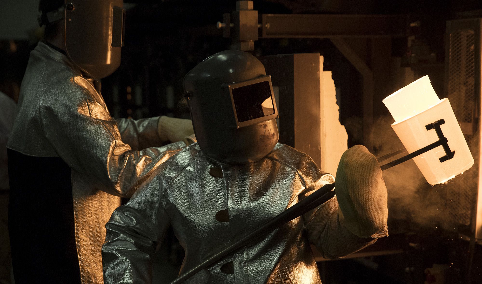 A worker pulls a crucible of molten glass from a furnace in Corning, New York