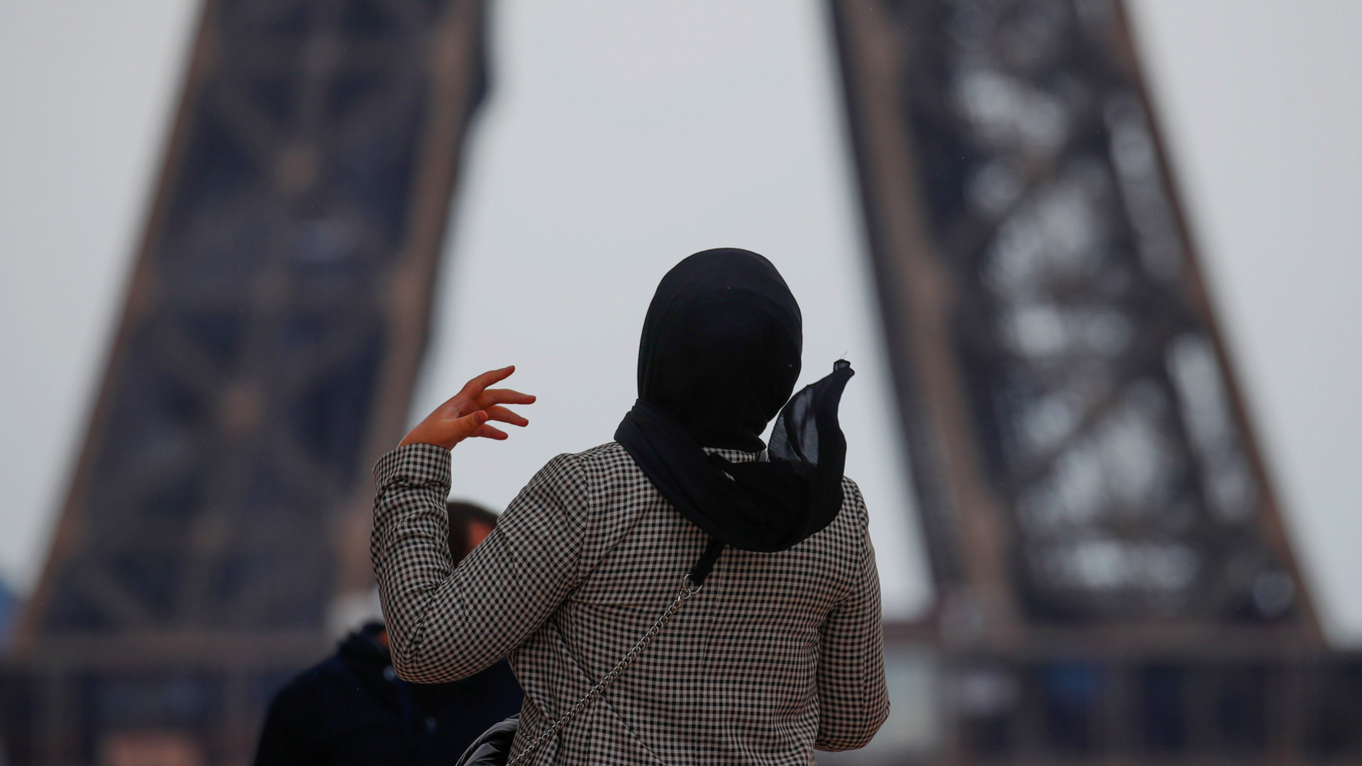 A photo of someone from the back as they're looking up at the Eiffel tower.