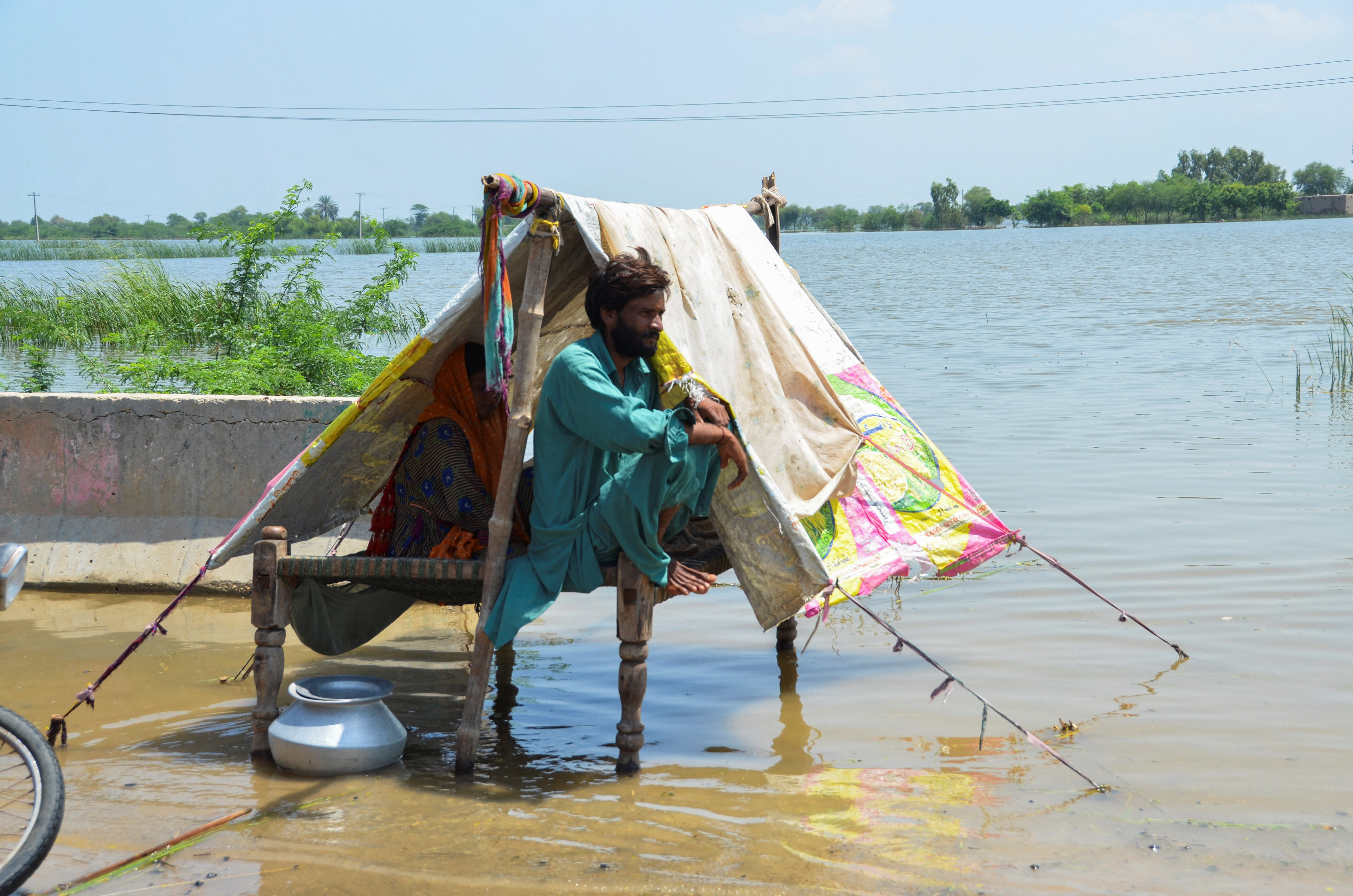 A family, affected by flood, sits in a tent amid rising flood waters