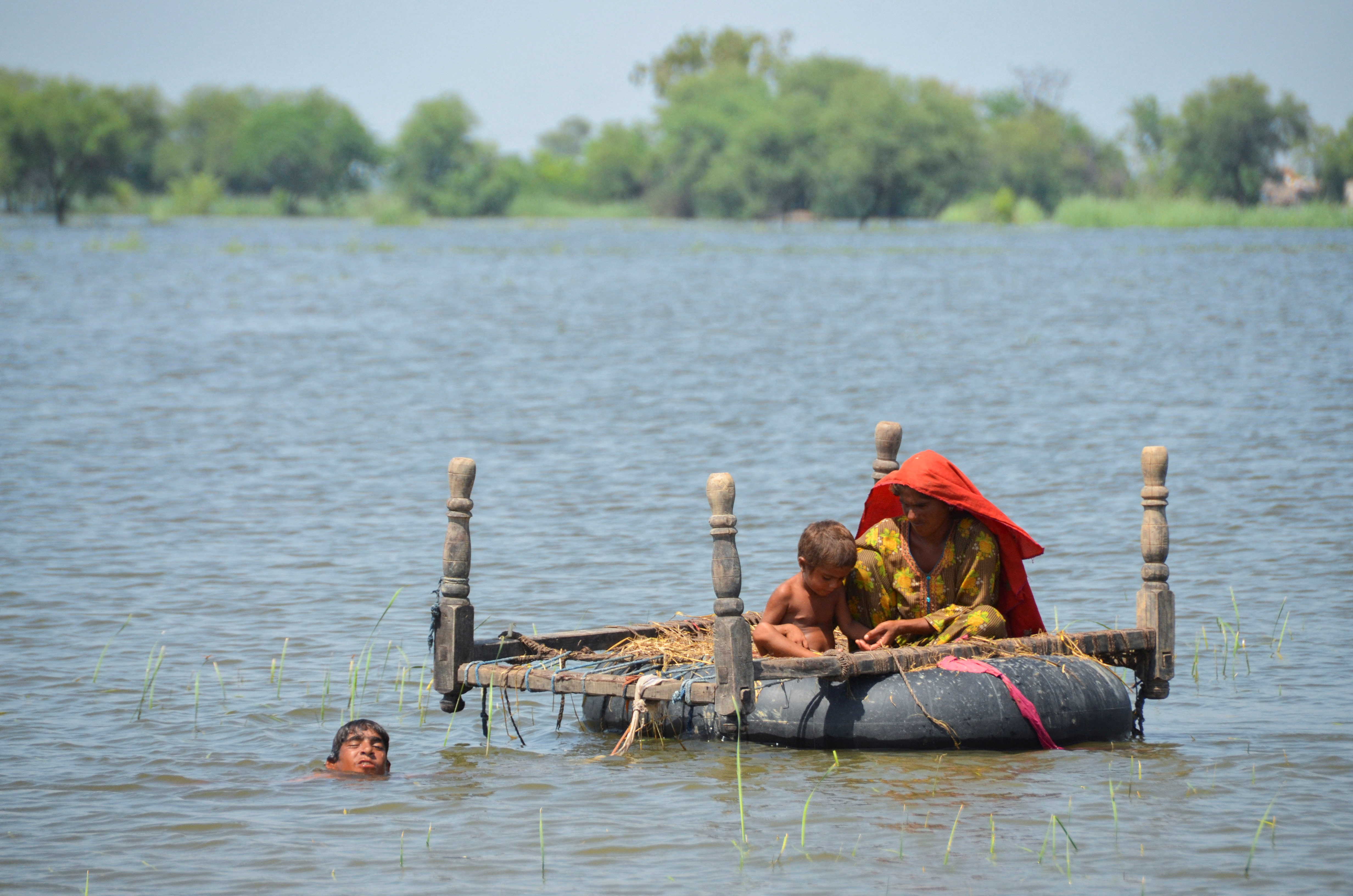 Flood victims use an inflatable tube as they travel in flood waters