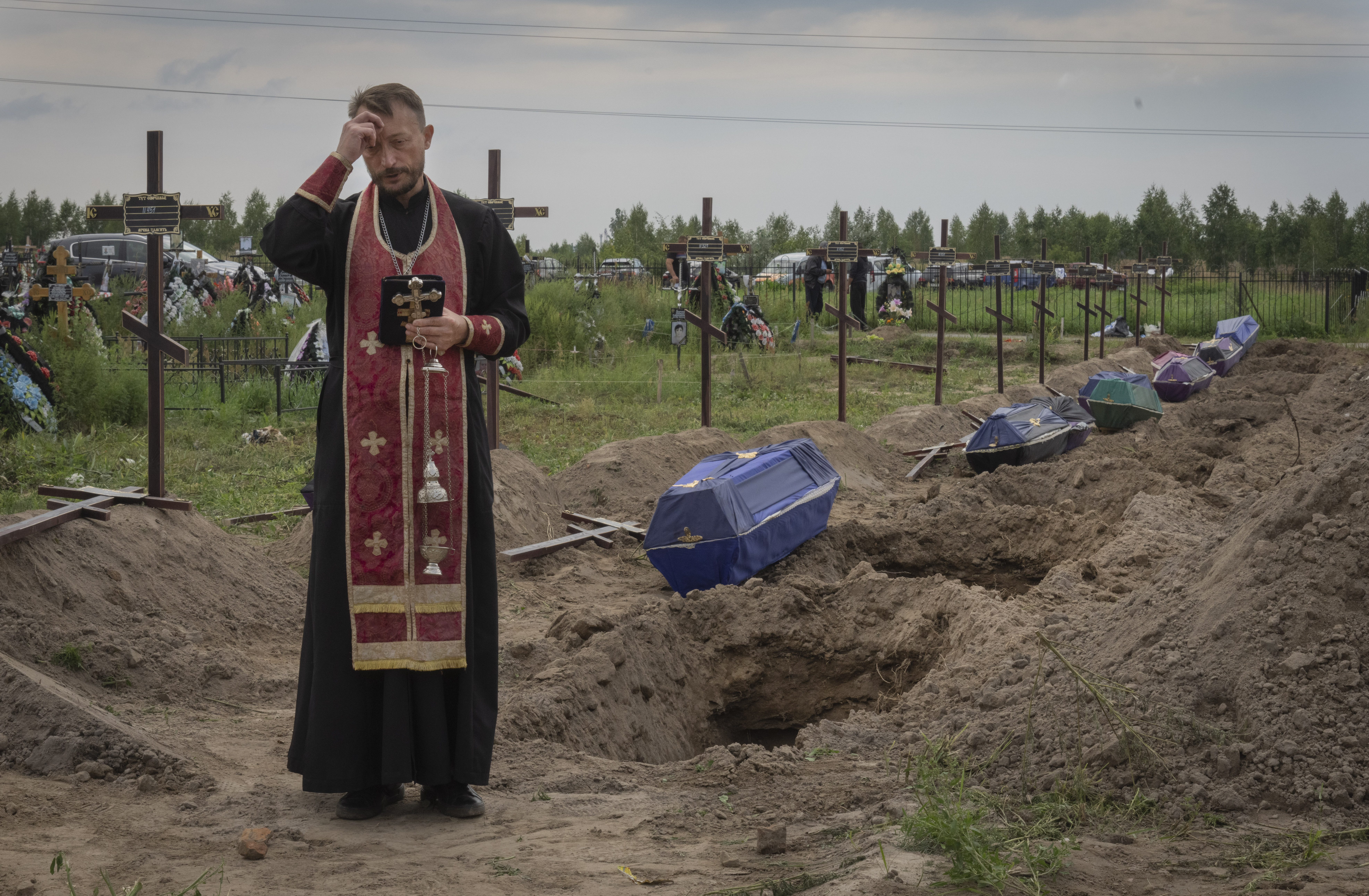 A priest prays for unidentified civilians killed by Russian troops during Russian occupation in Bucha, on the outskirts of Kyiv, Ukraine, Thursday