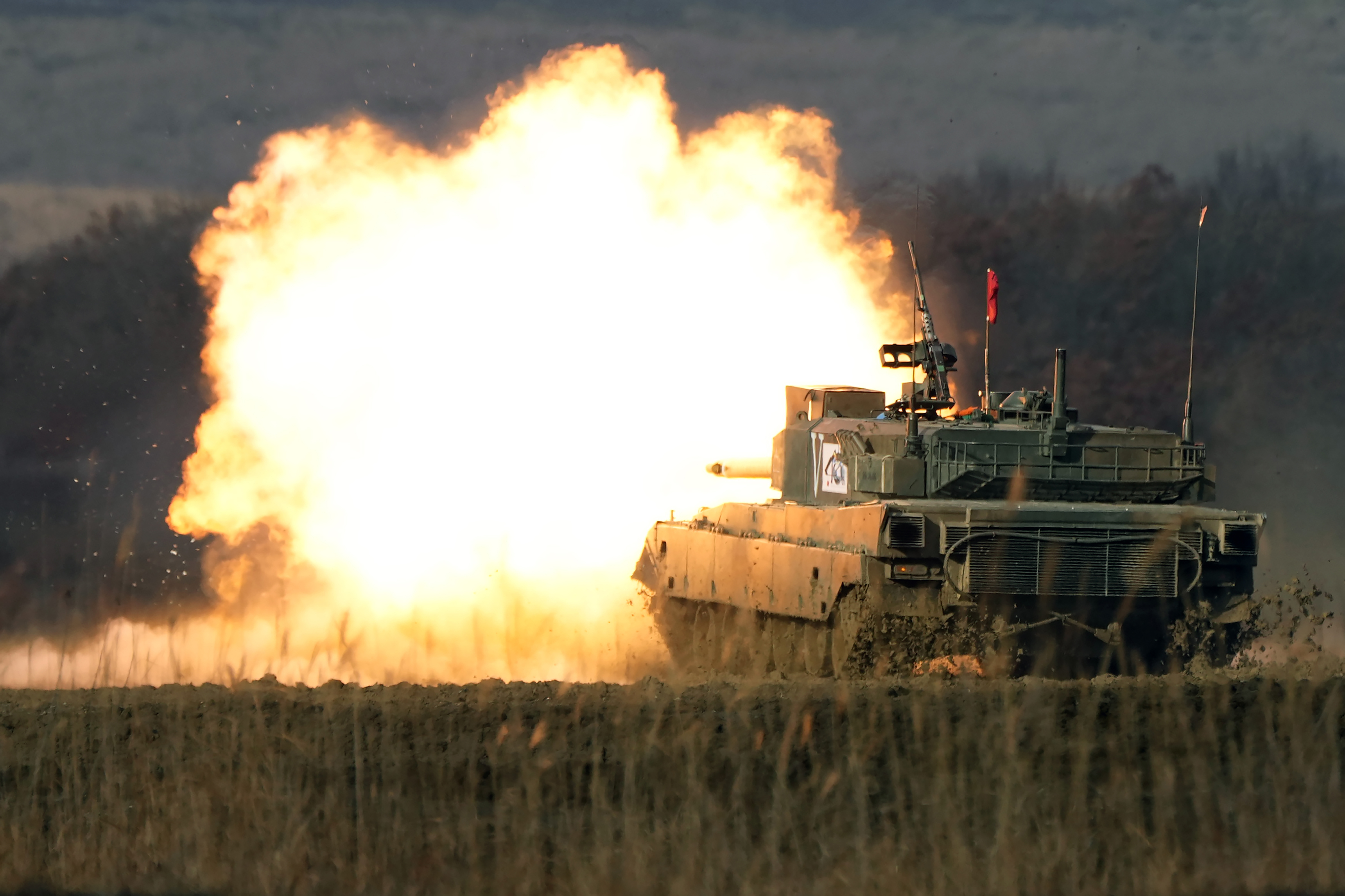 A Japanese tank fires its gun creating a ball of orange flame and smoke during exercises 
