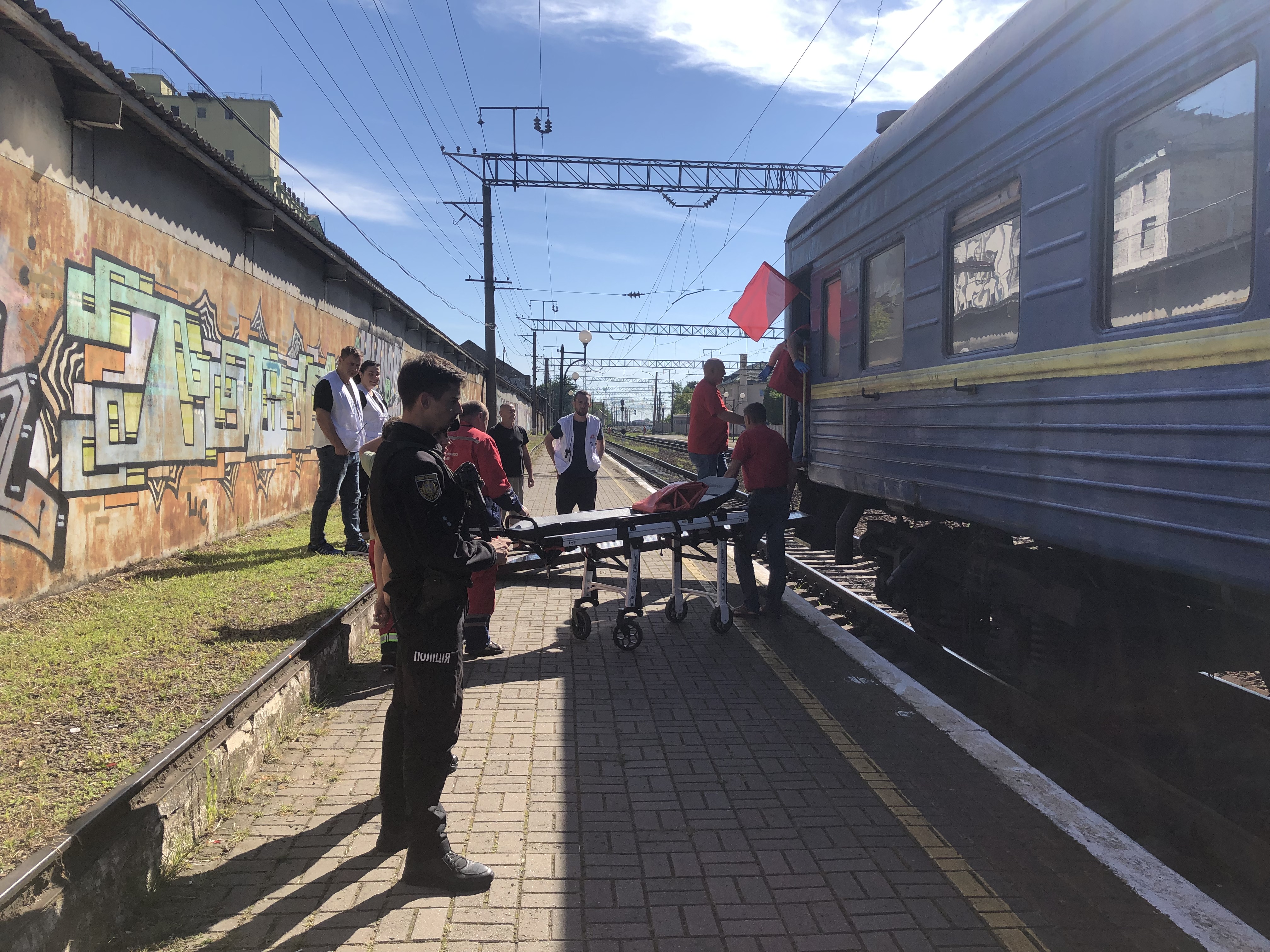 A photo of paramedics with a bed standing outside of a train.