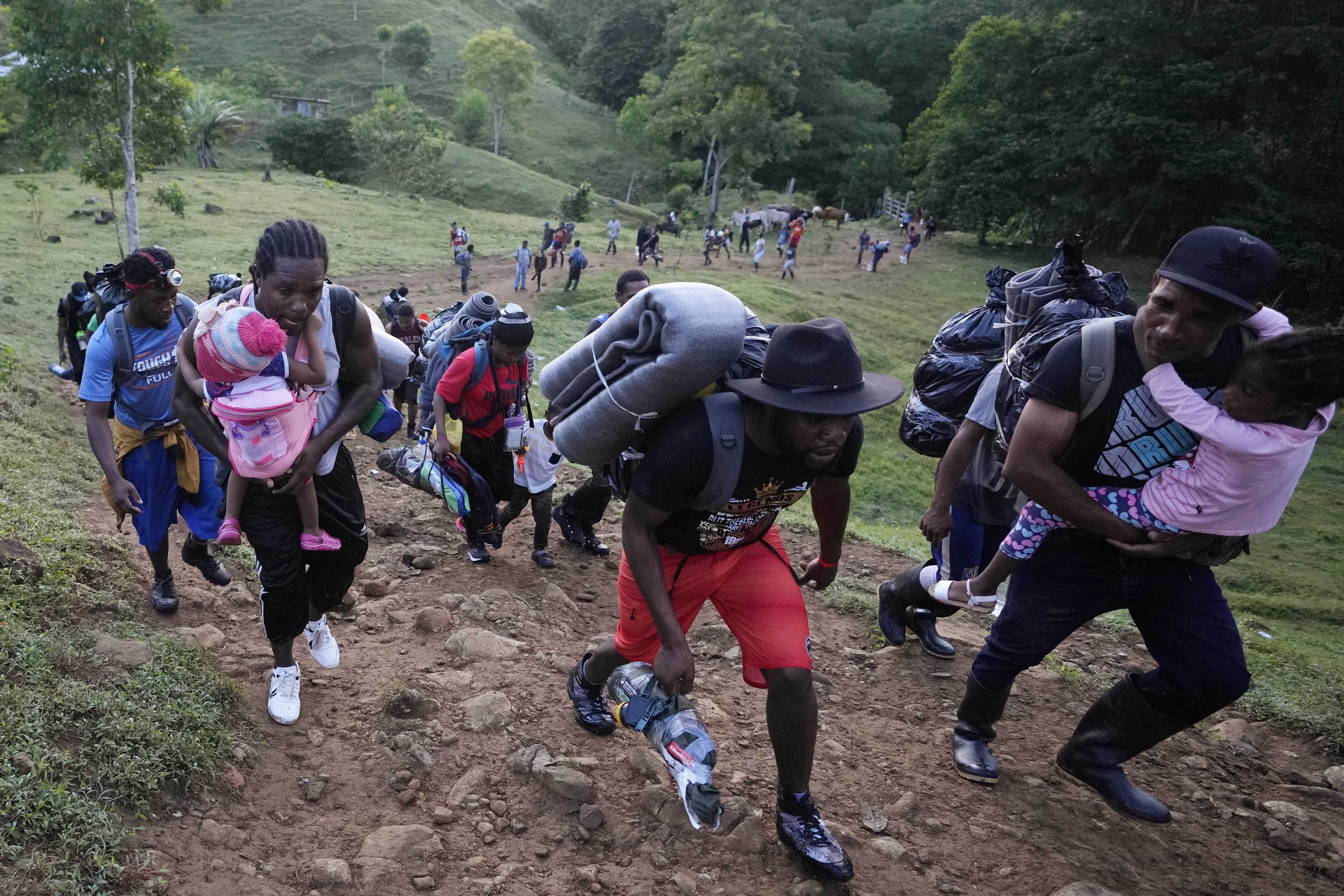 Refugees and migrants, who are mostly Haitians, climb up a hill on their way to crossing the Darien Gap from Colombia into Panama.