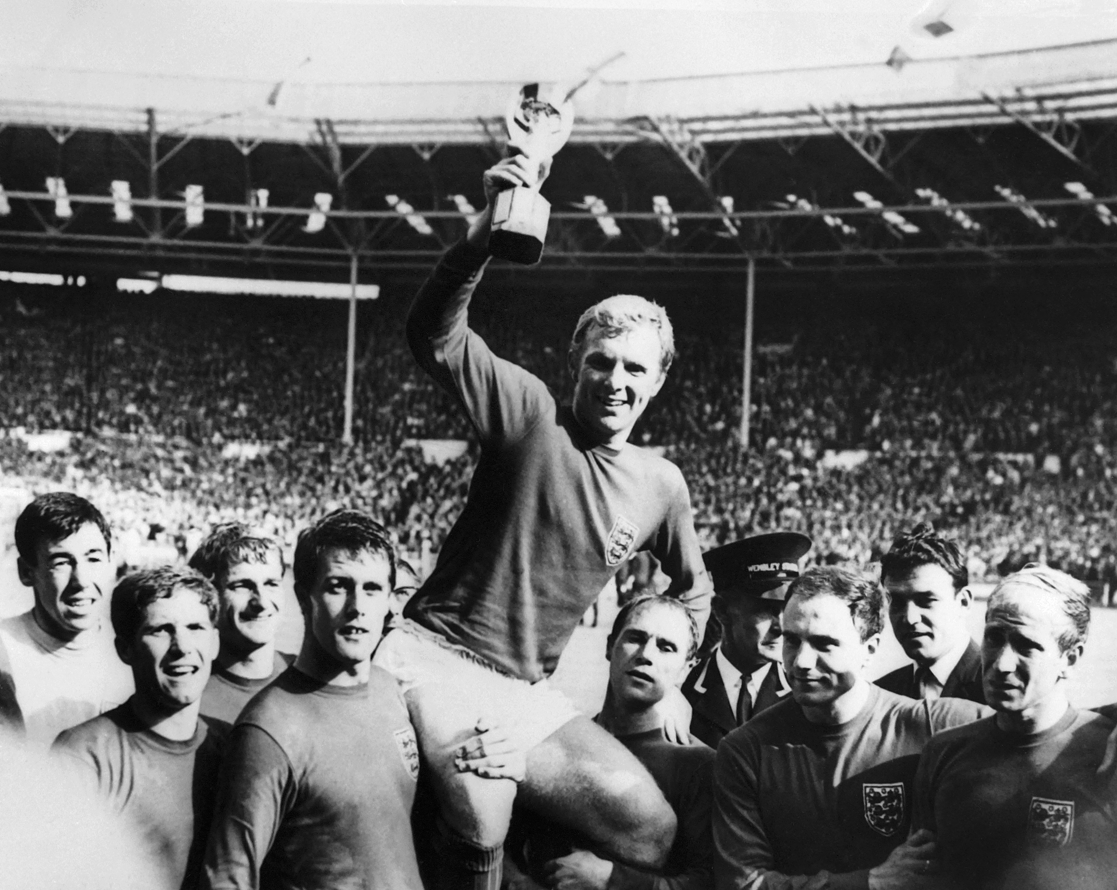 England's national soccer team captain Bobby Moore holds aloft the Jules Rimet trophy as he is carried by his teammates following England's victory over Germany