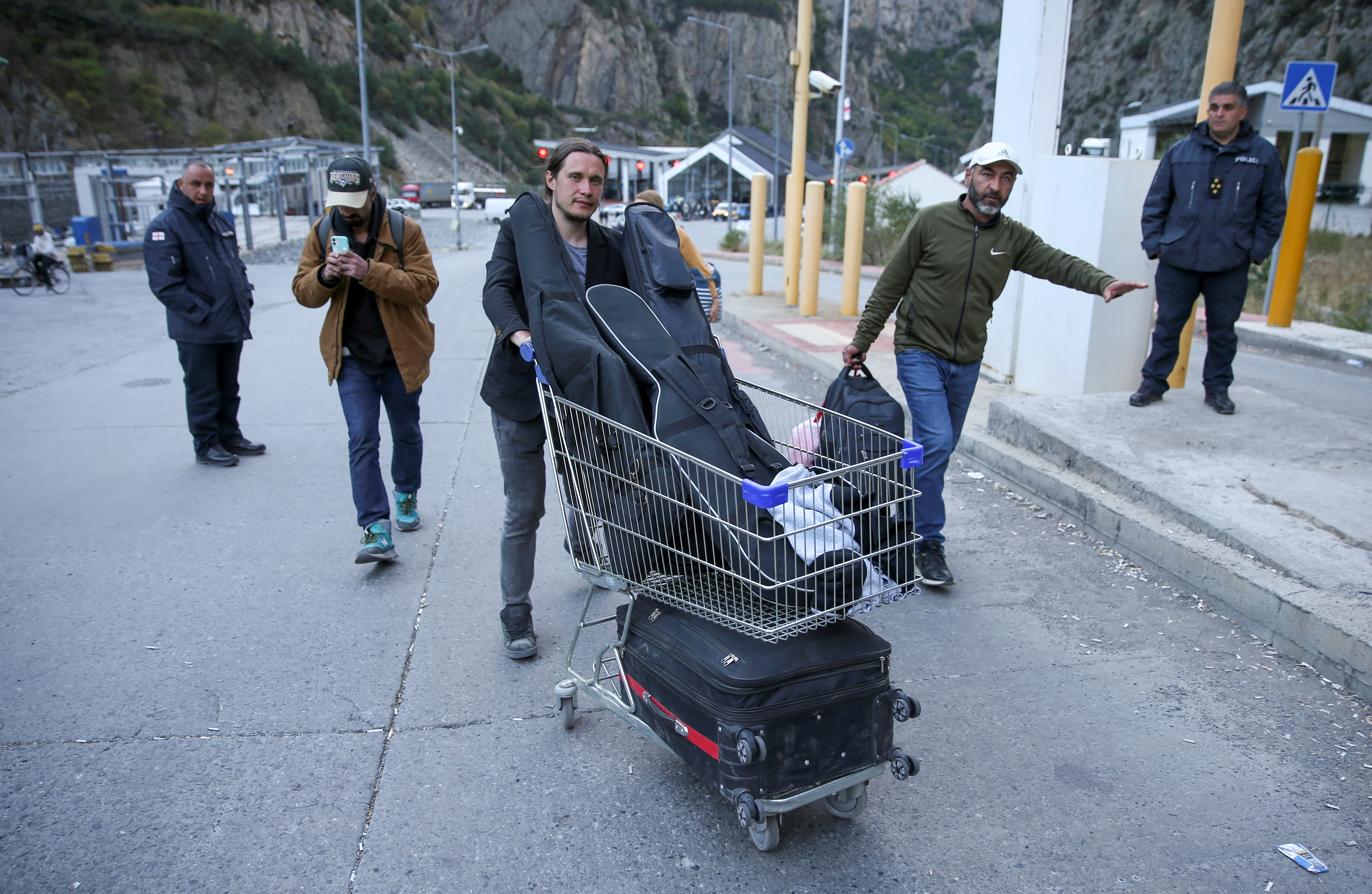 Travellers walk after crossing the border with Russia at a frontier checkpoint in Georgia on September 28, 2022