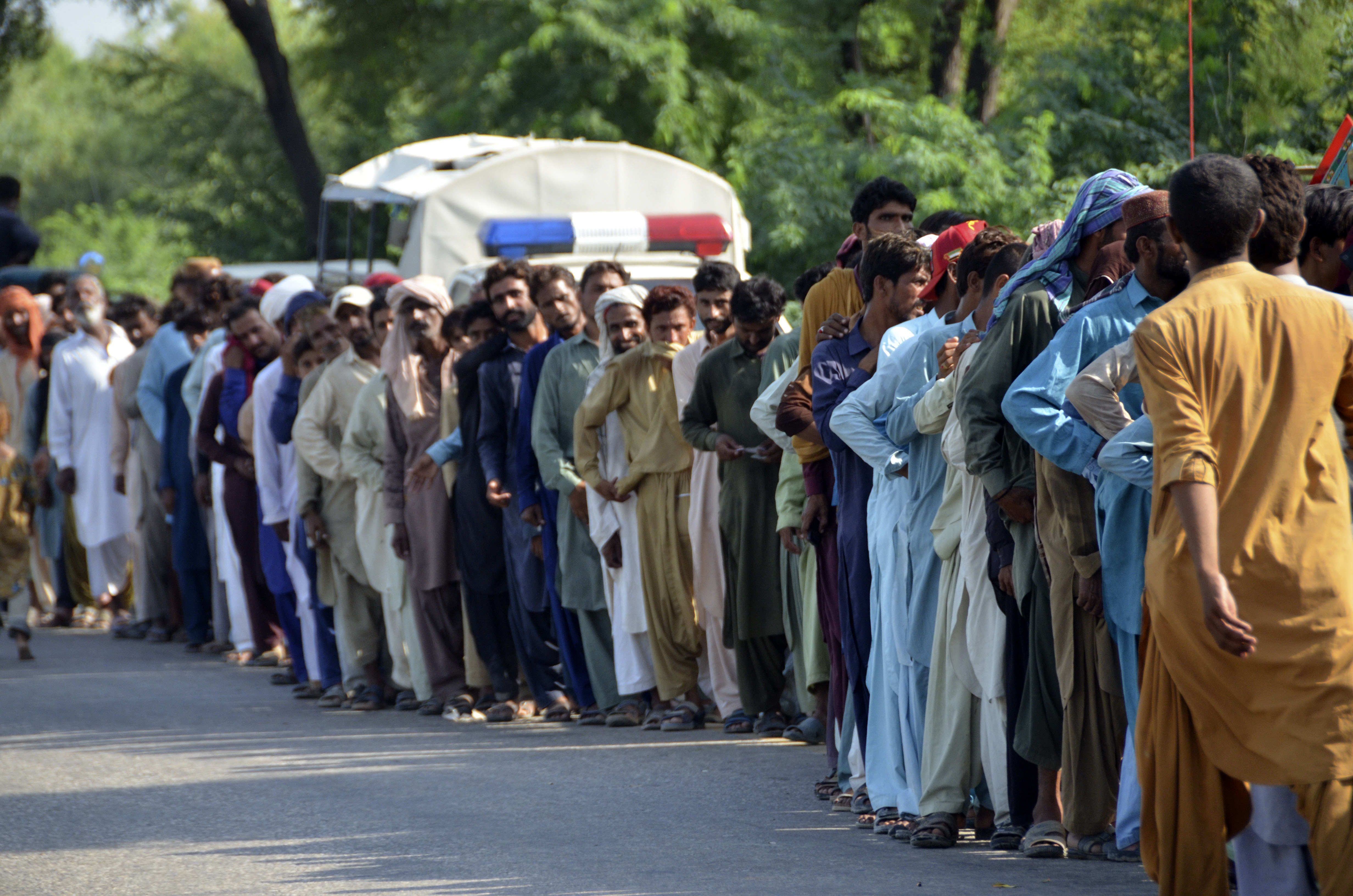 A long line of men made colourful by their various clothing.