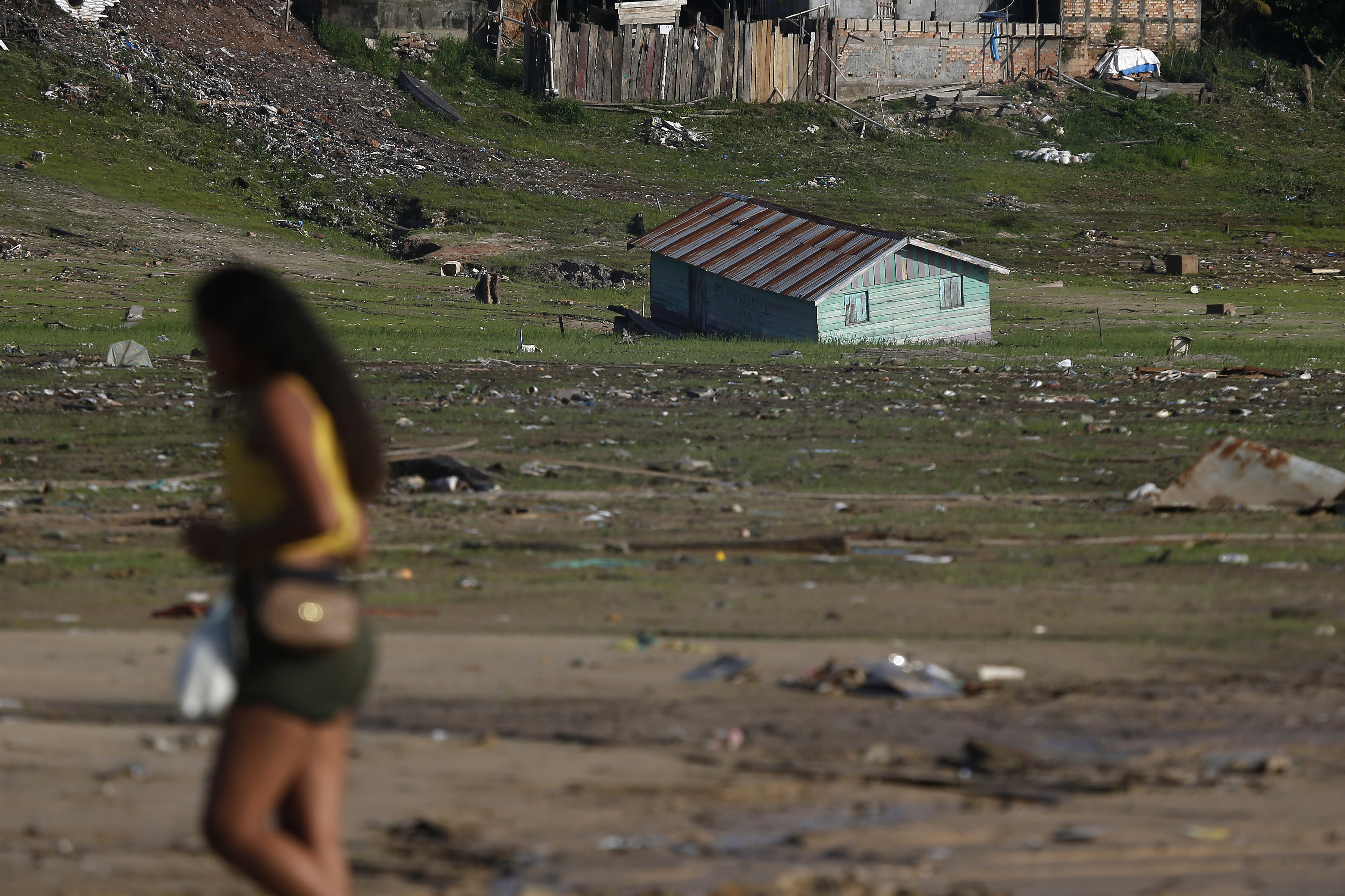 A woman walks near a houseboat impacted by the drought near the Solimões River, in Tefe, Amazonas state, Brazil