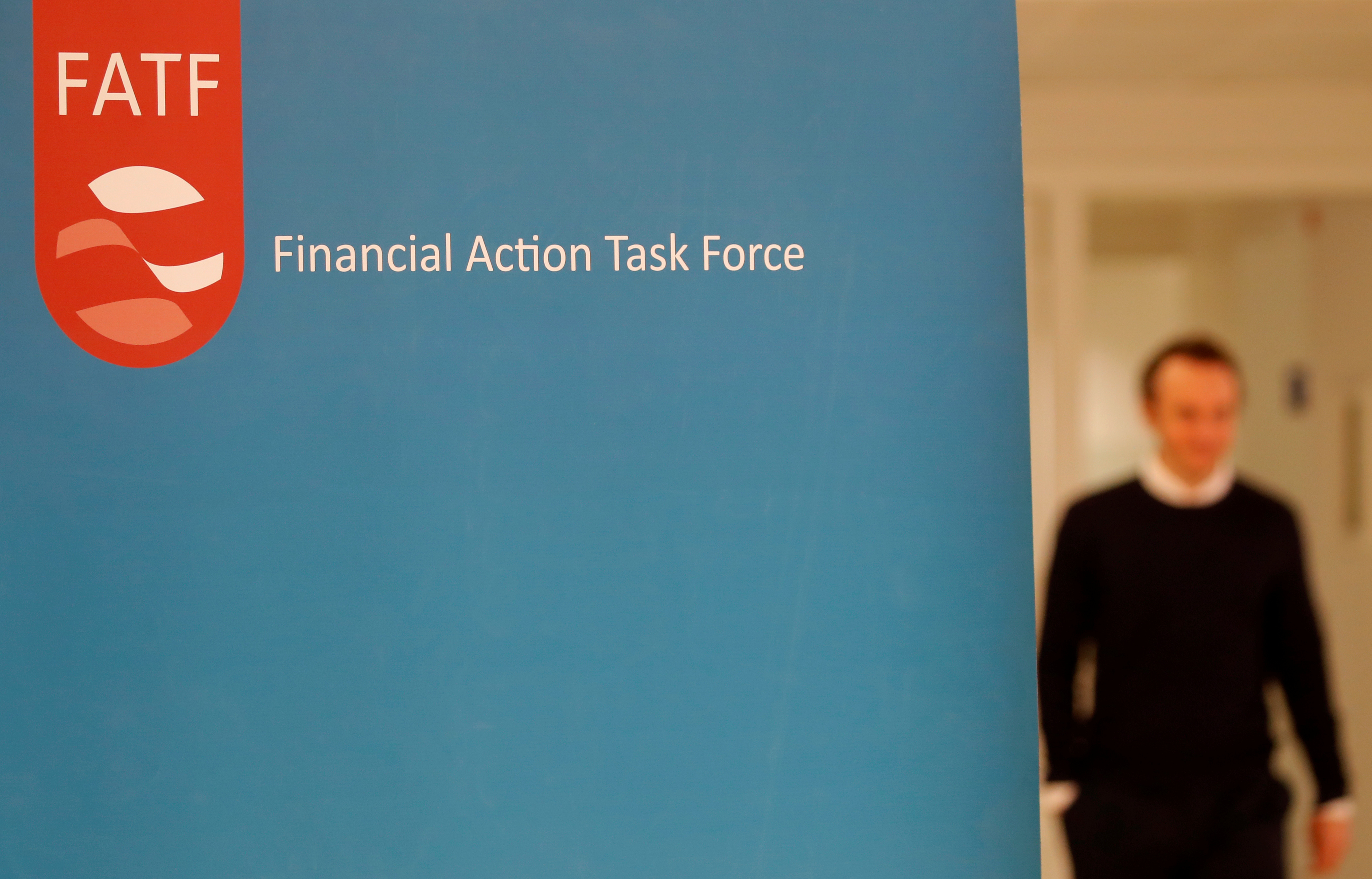 Financial Action Task Force logo pictured with an out-of-focus man walking in the background.