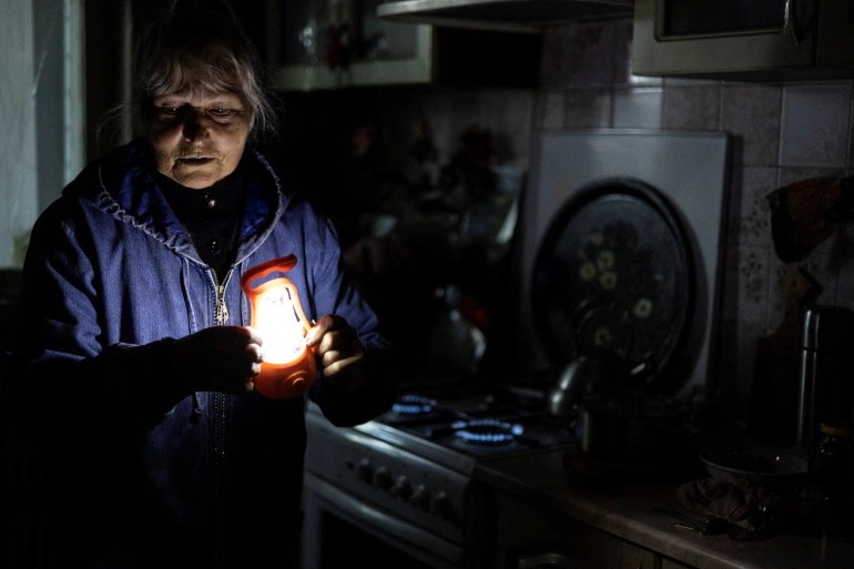 Olga Kobzar stands in her kitchen, demonstrating how she heats her apartment by a gas stove cooktop in Kharkiv, Ukraine.