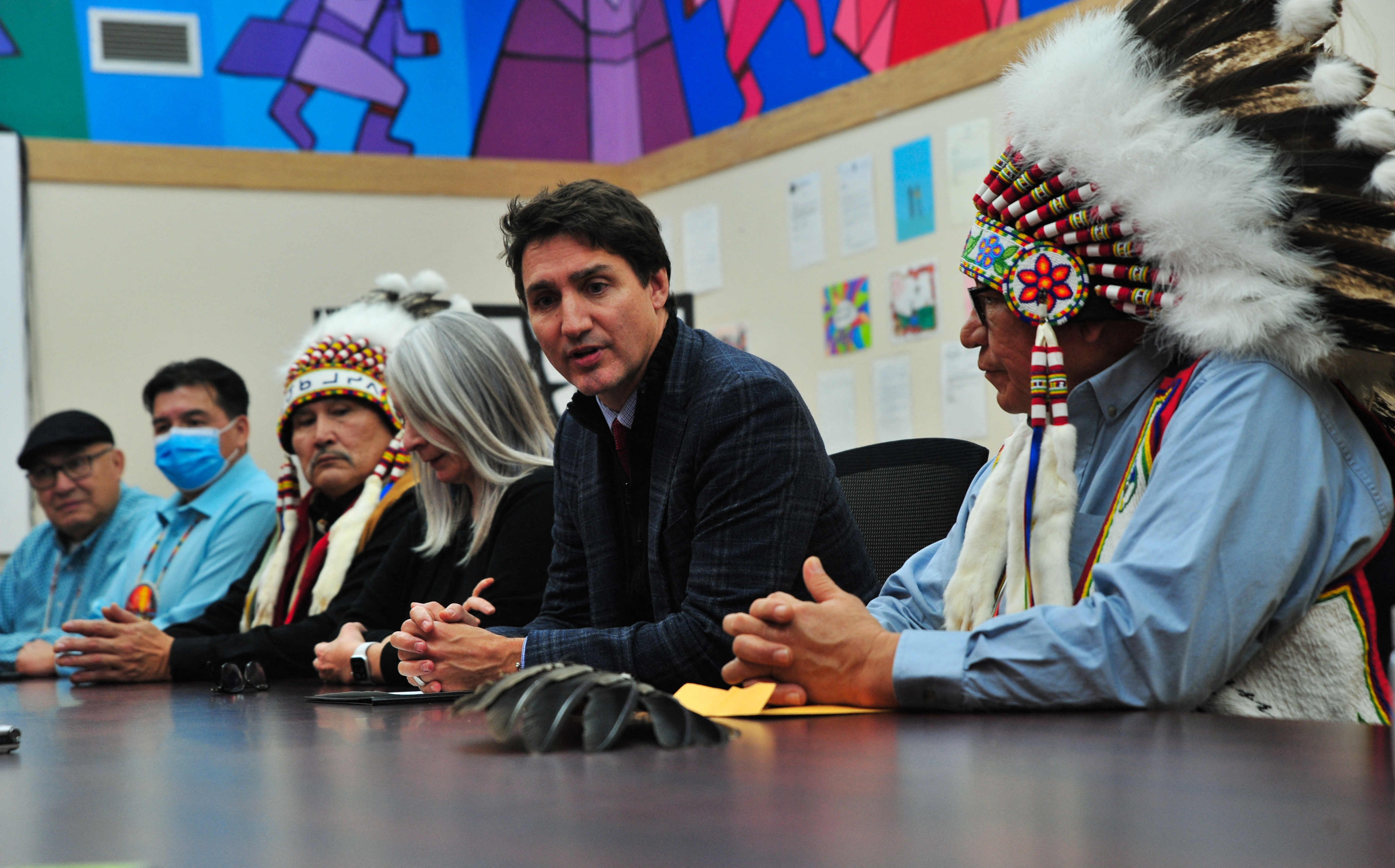 Indigenous leaders in James Smith Cree Nation sitting with Justin Trudeau at a long table.