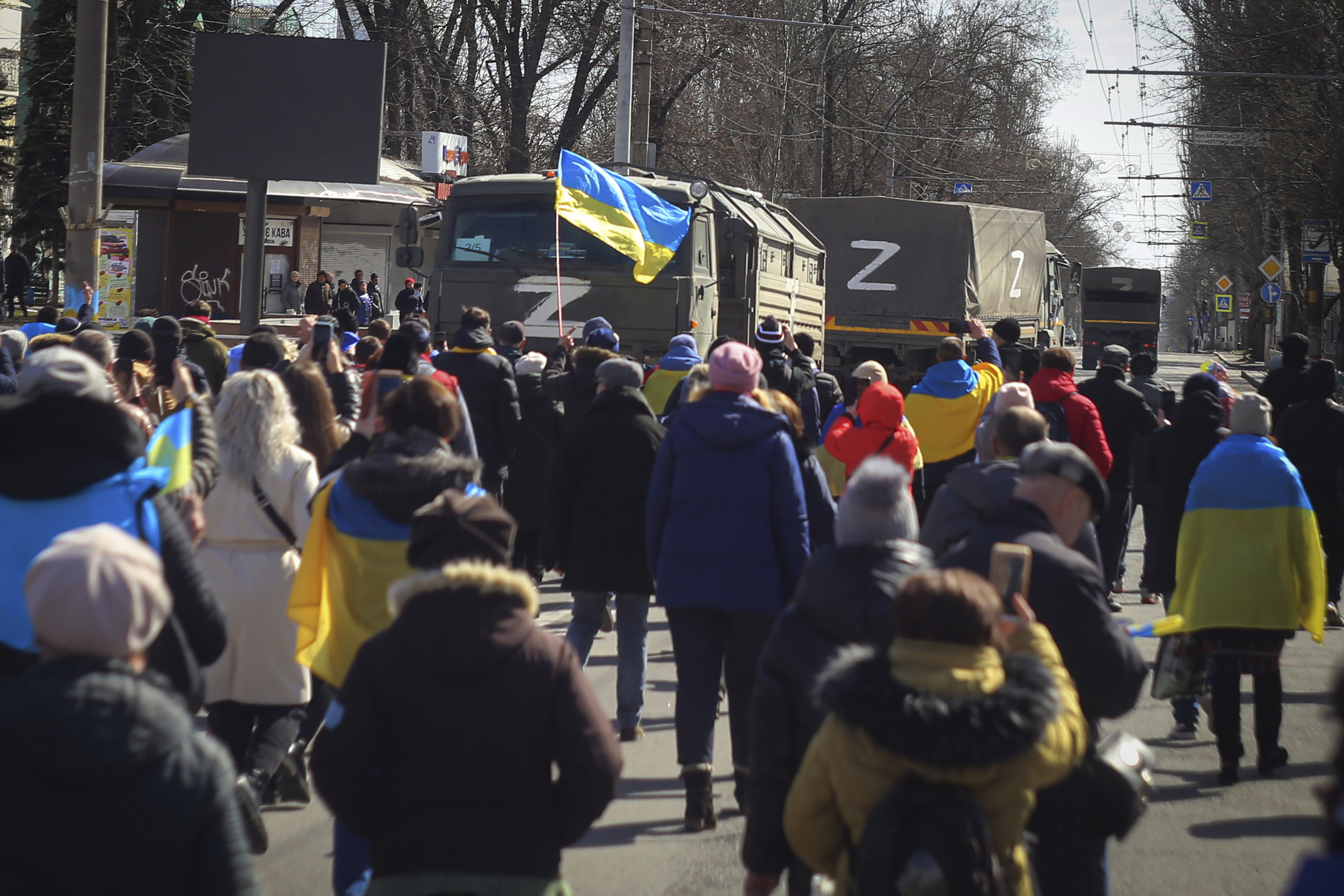 People with Ukrainian flags walk towards Russian army trucks during a rally against the Russian occupation in Kherson on March 20