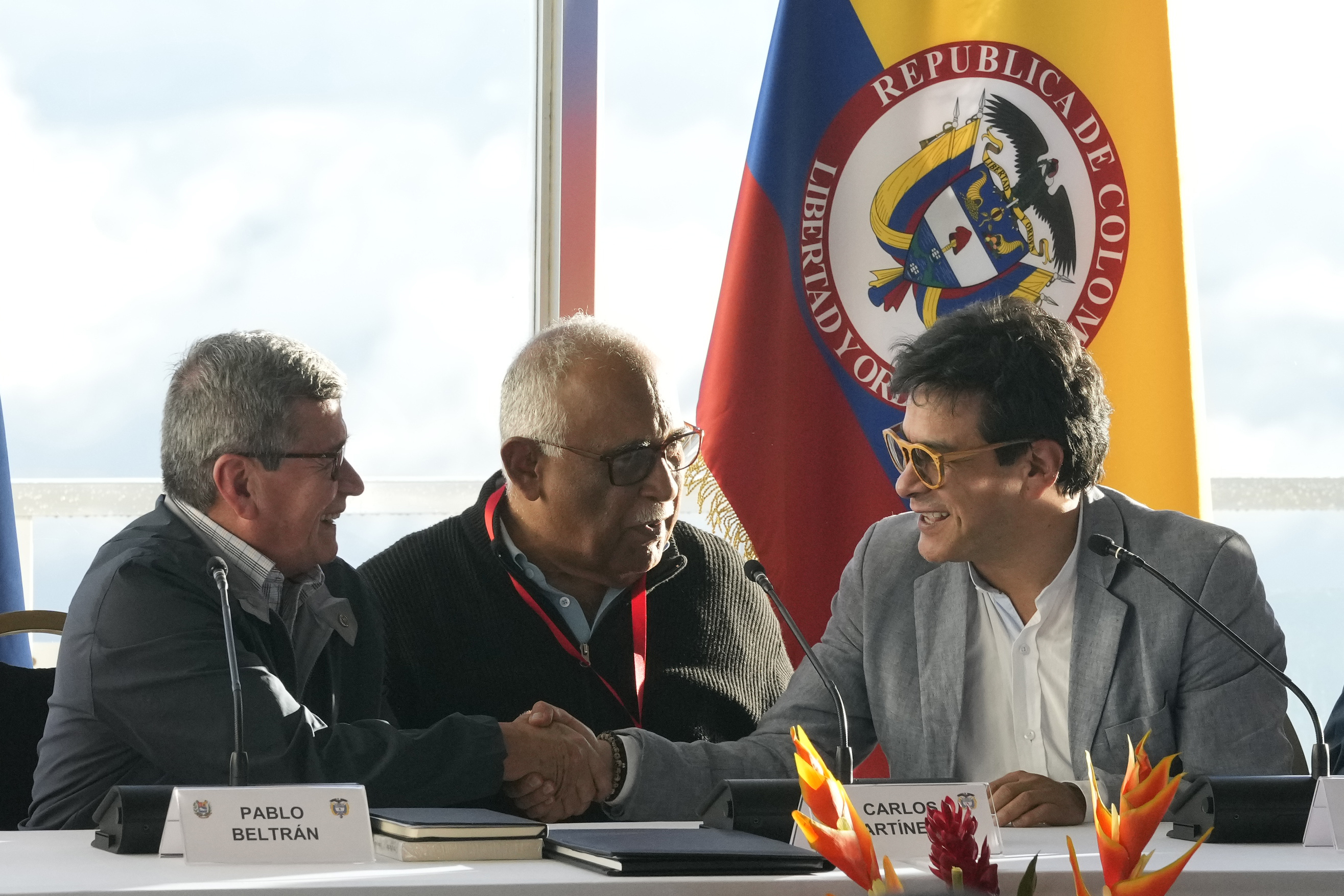 Pablo Beltran, representing the Colombian guerrilla National Liberation Army (ELN), left, shakes hands with Ivan Danilo Rueda, High Commissioner for Peace on behalf of the Colombian government, at the restart of peace talks after a suspension of more that three years, at the hotel Humboldt in Caracas, Venezuela, Monday Nov. 21, 2022. The man at center is Carlos Martinez, a retired Venezuelan military official serving as guarantor. (AP Photo/Ariana Cubillos)