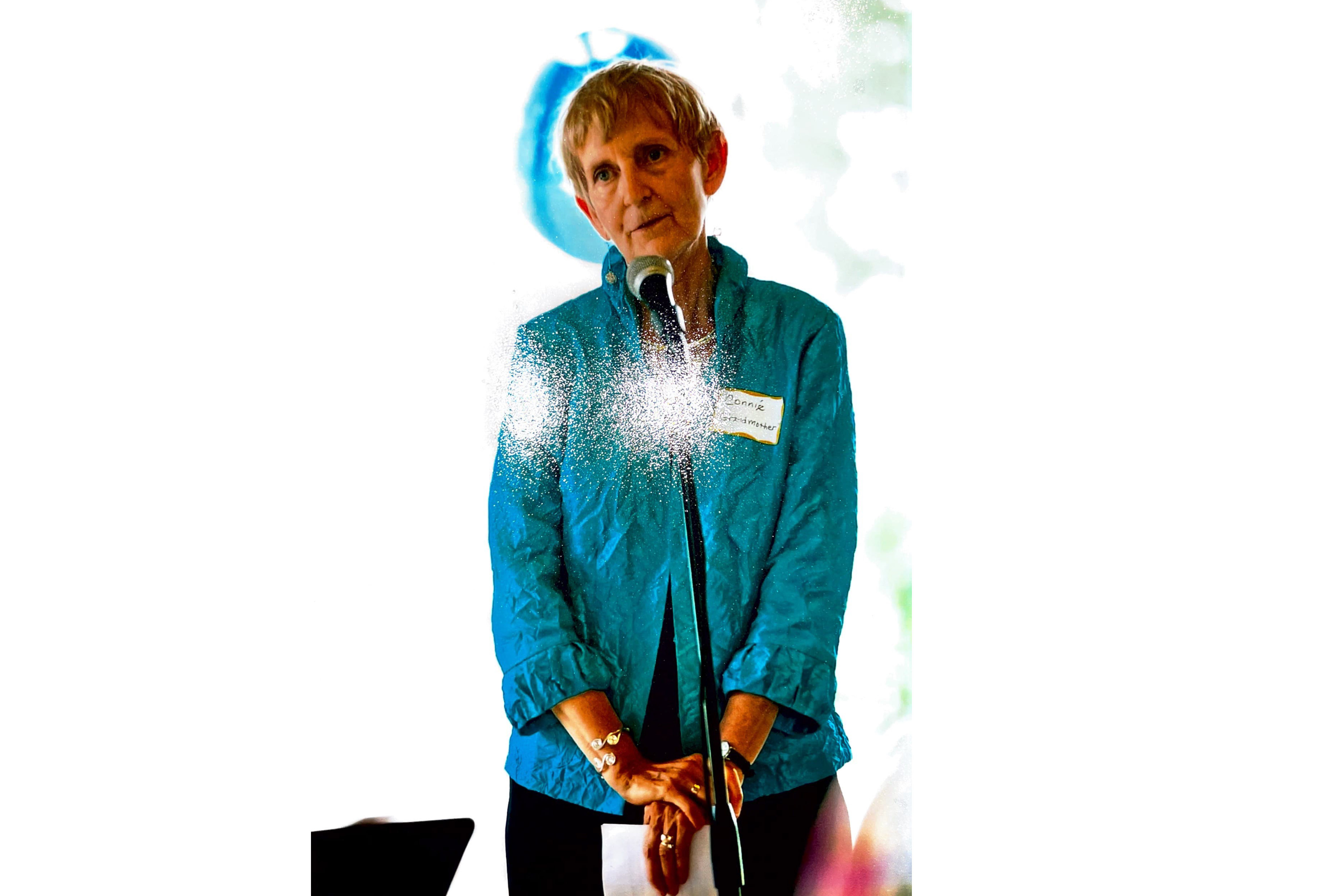 A photo of a person standing in front of a microphone.