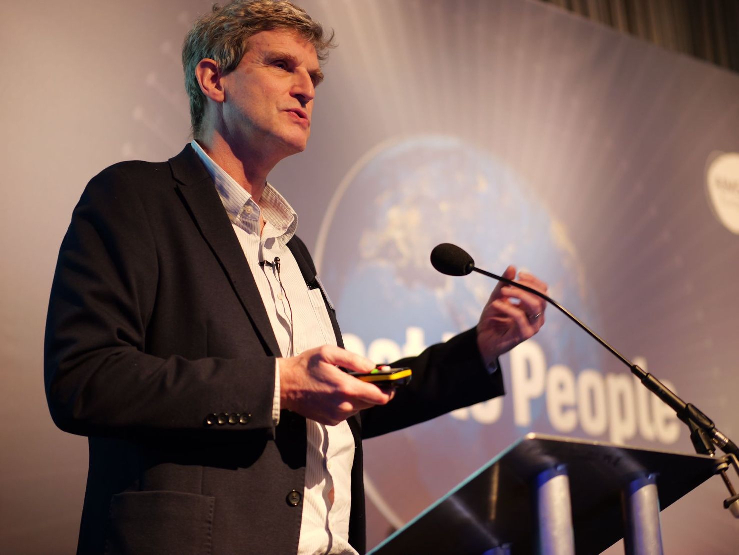 Walker speaking at a podium with clicker in one hand