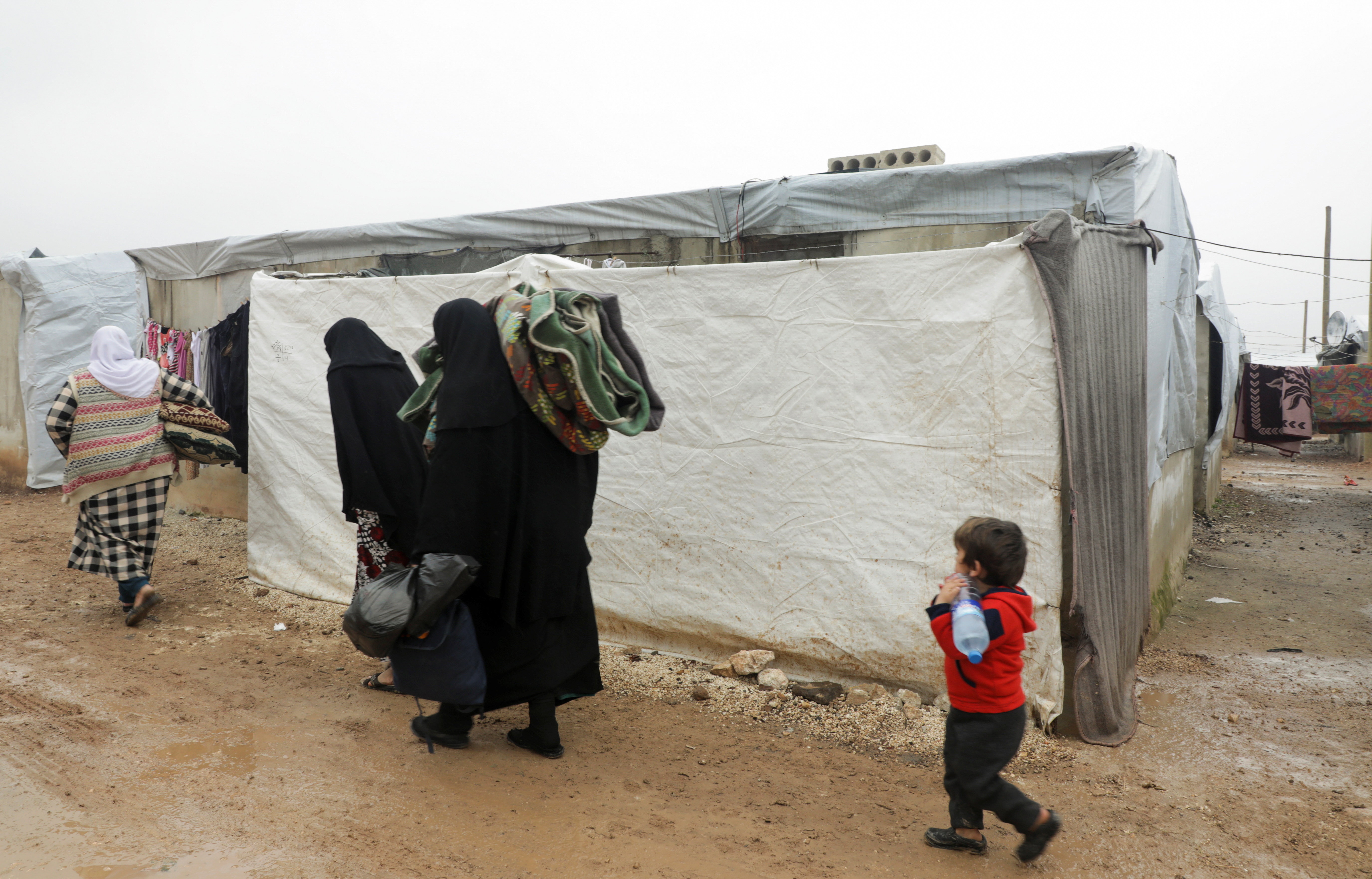 Internally displaced Syrians walk together near tents at a camp in Azaz, Syria March 1, 2022. Picture taken March 1, 2022. REUTERS/Mahmoud Hassano
