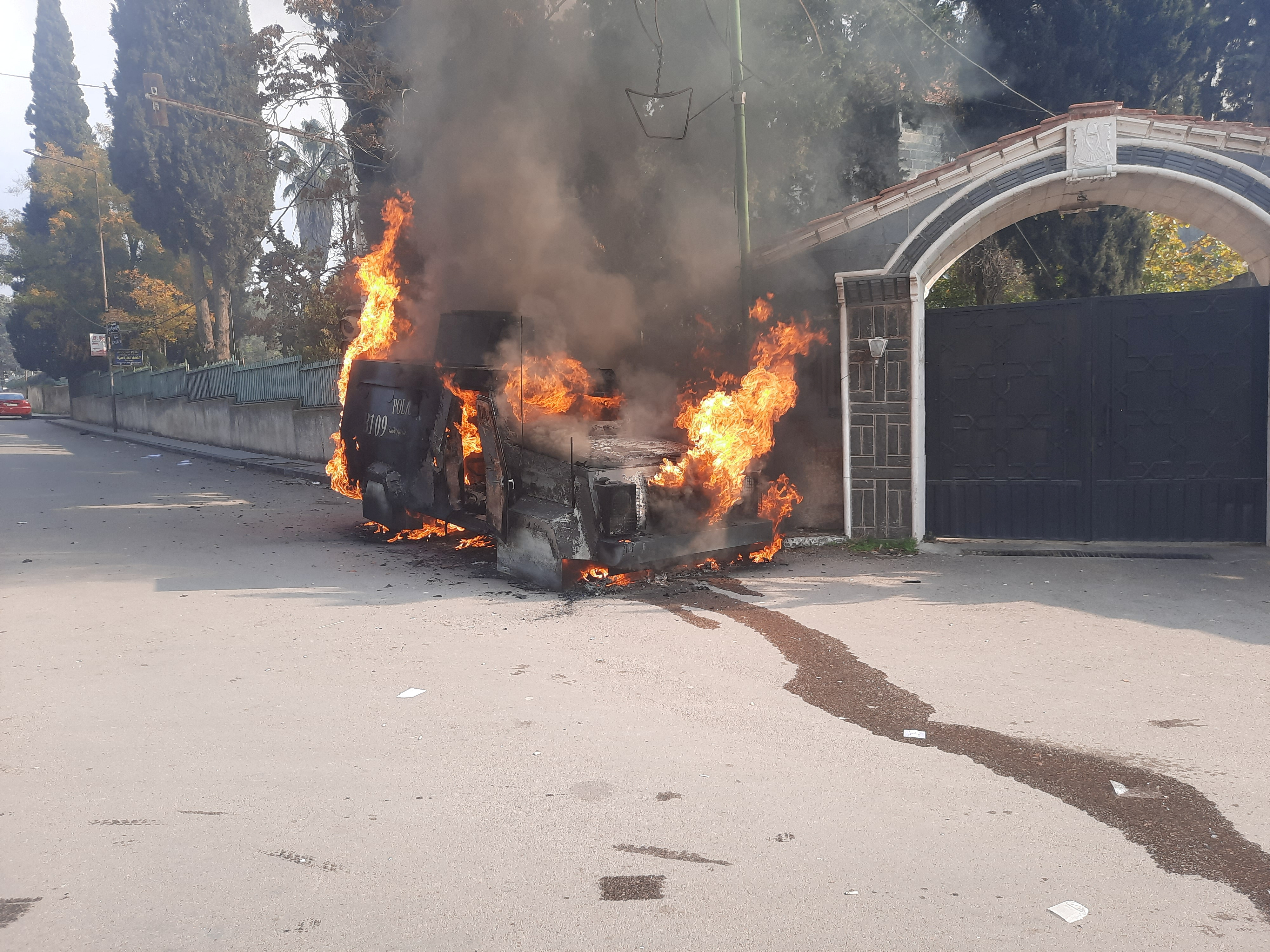 A police vehicle burns as people take part in a protest in Sweida, Syria.