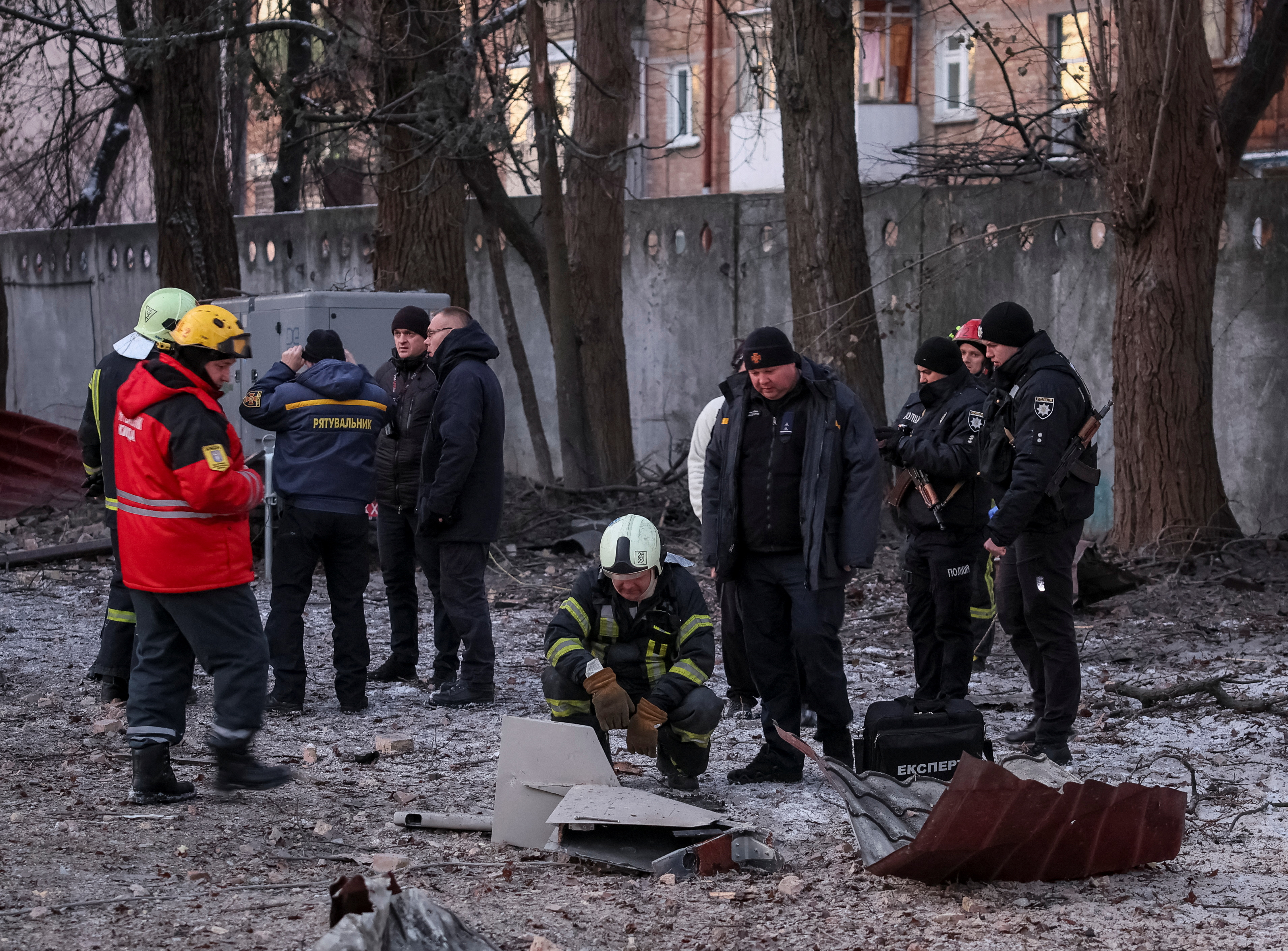 Rescuers and police officers examine parts of the drone at the site of a building destroyed by a Russian drone attack