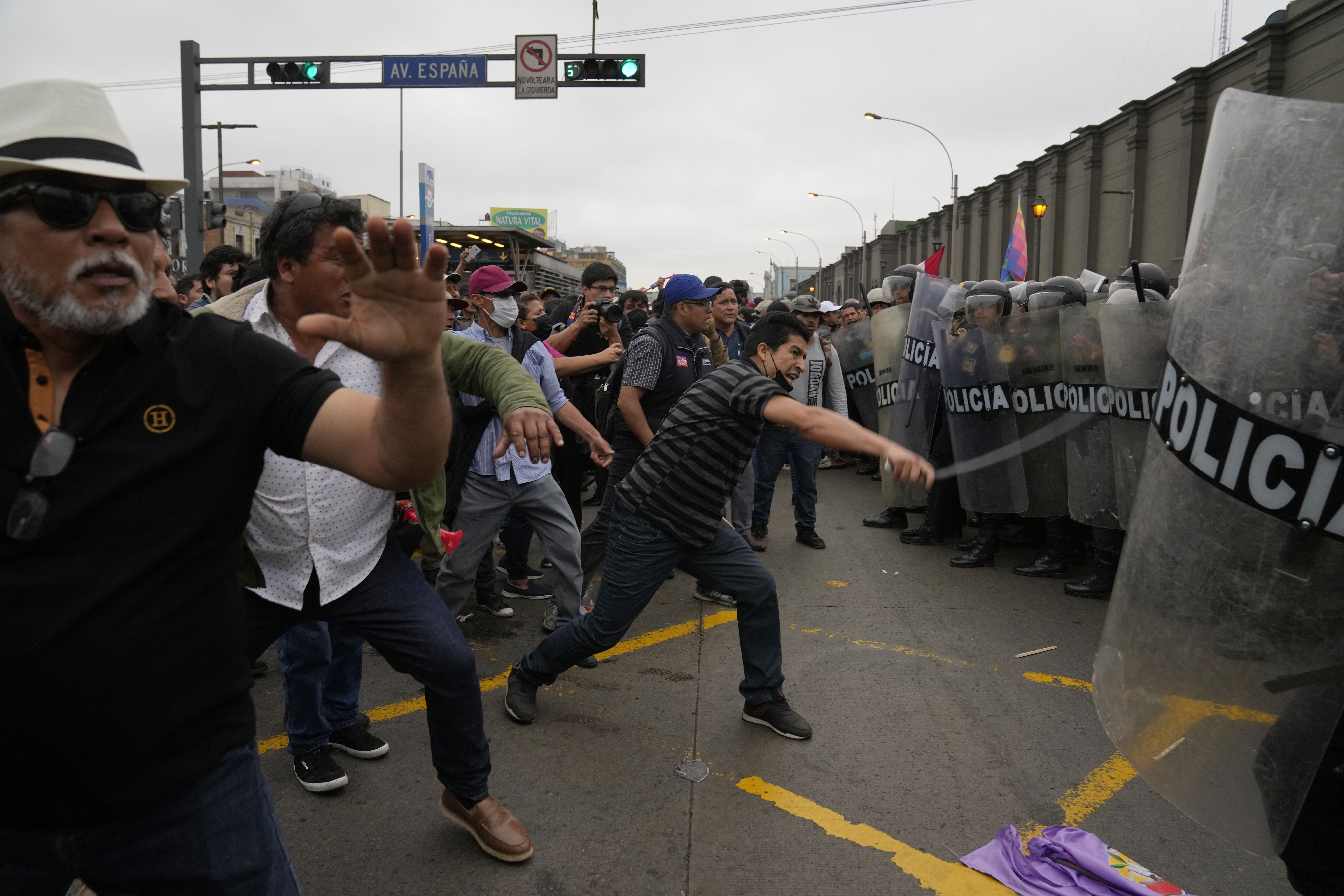 Supporters of former President Pedro Castillo confront riot police surrounding the police station where Castillo arrived earlier, in Lima, Peru, Wednesday, Dec. 7, 2022. Peru's Congress removed Castillo from office Wednesday, voting to replace him with the vice president, shortly after Castillo decreed the dissolution of the legislature ahead of a scheduled vote to oust him. (AP Photo/Martin Mejia)