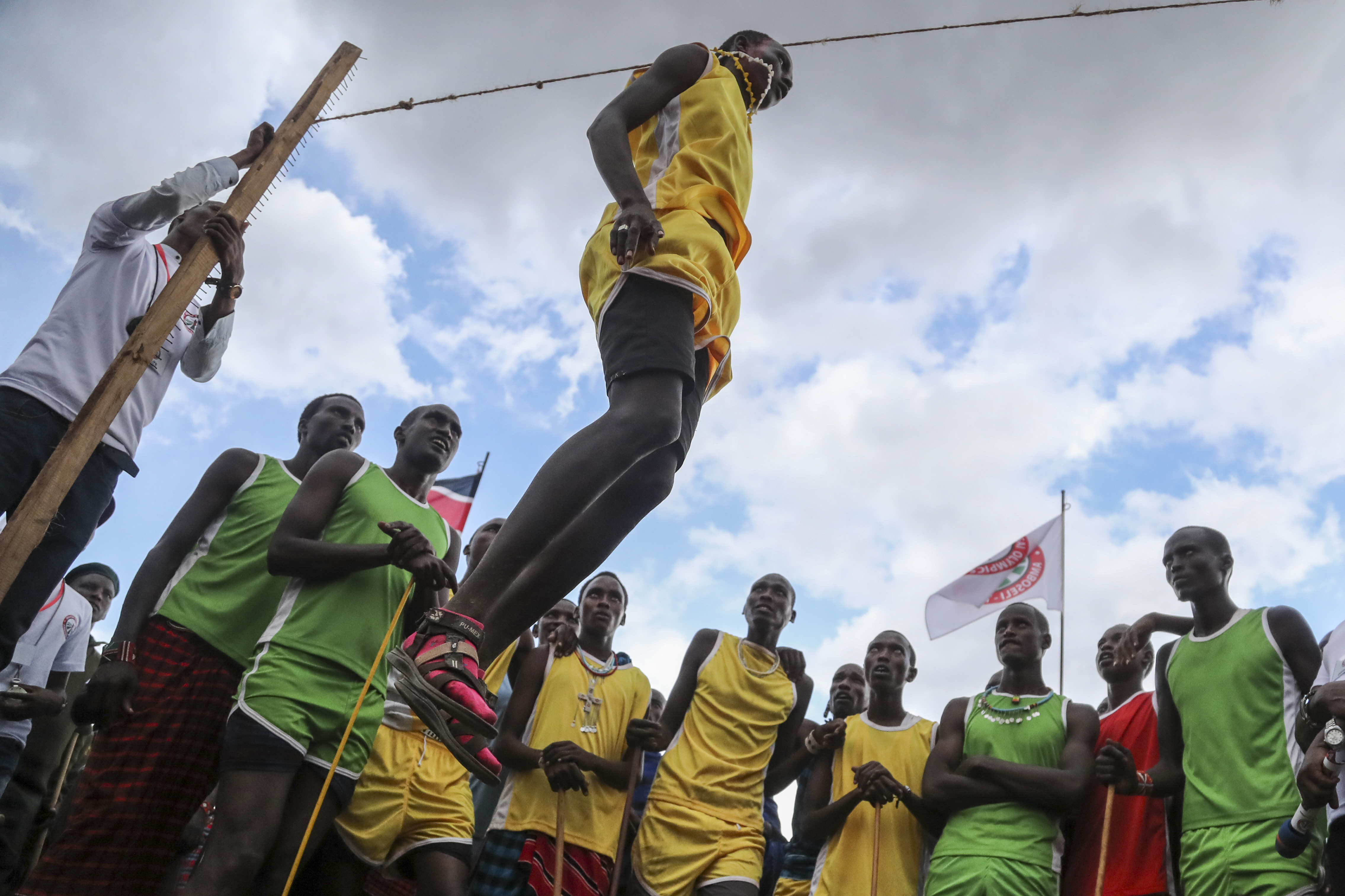 A Maasai man competes in the high-jump competition at the Maasai Olympics, surrounded by onlookers, in Kimana Sanctuary, Kenya.