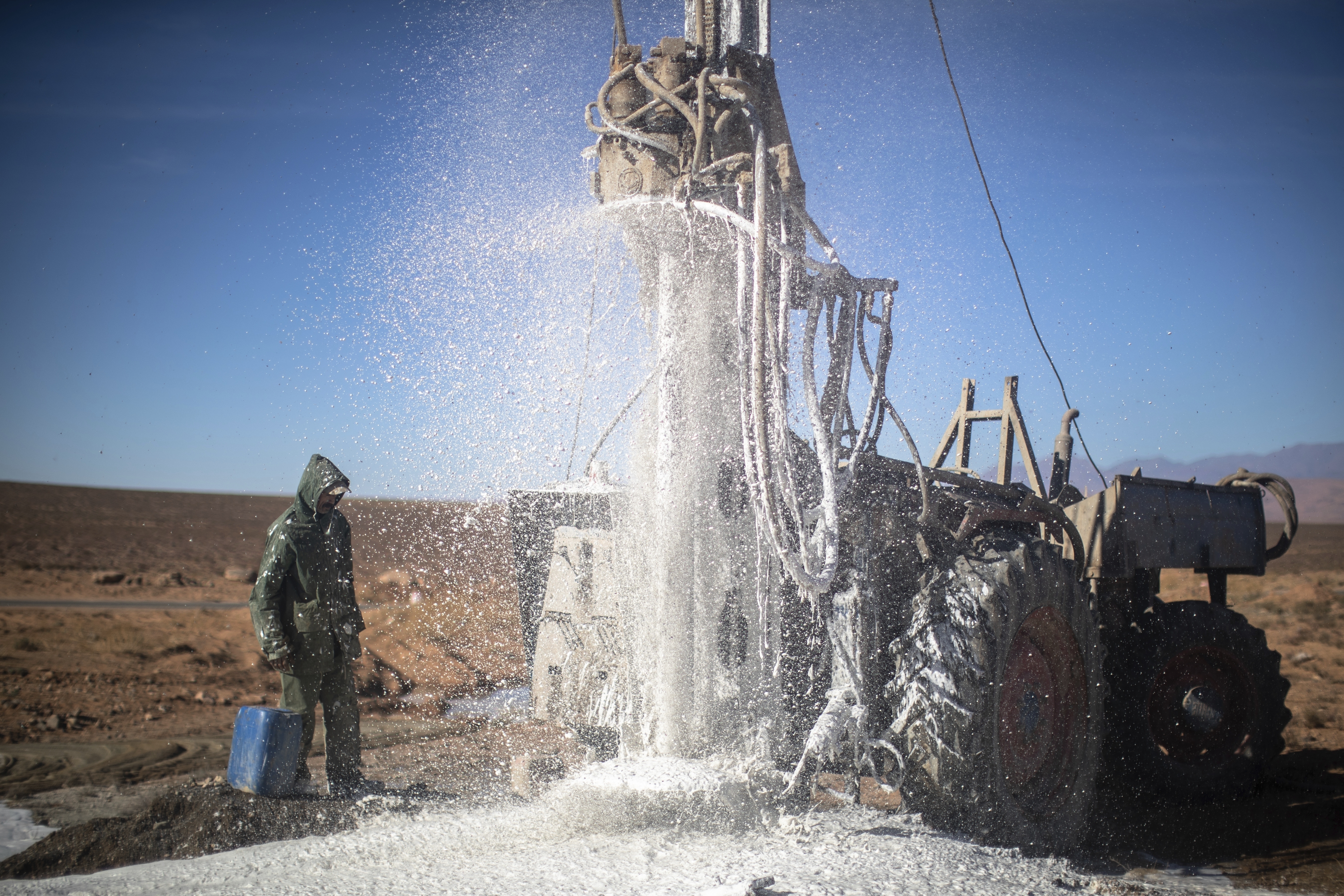 A worker watches as water flows from the ground during a well dig
