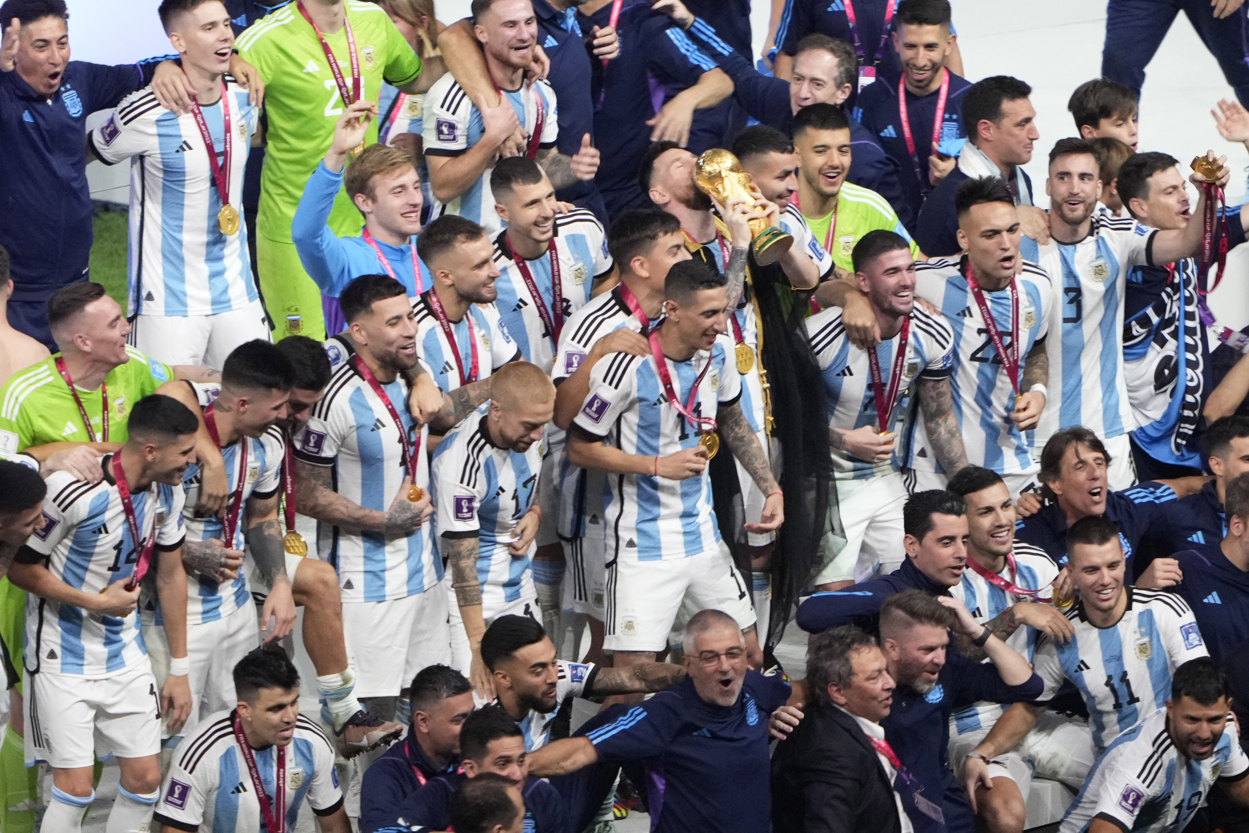 Lionel Messi kisses the World Cup trophy as the Argentinian team celebrate their victory.
