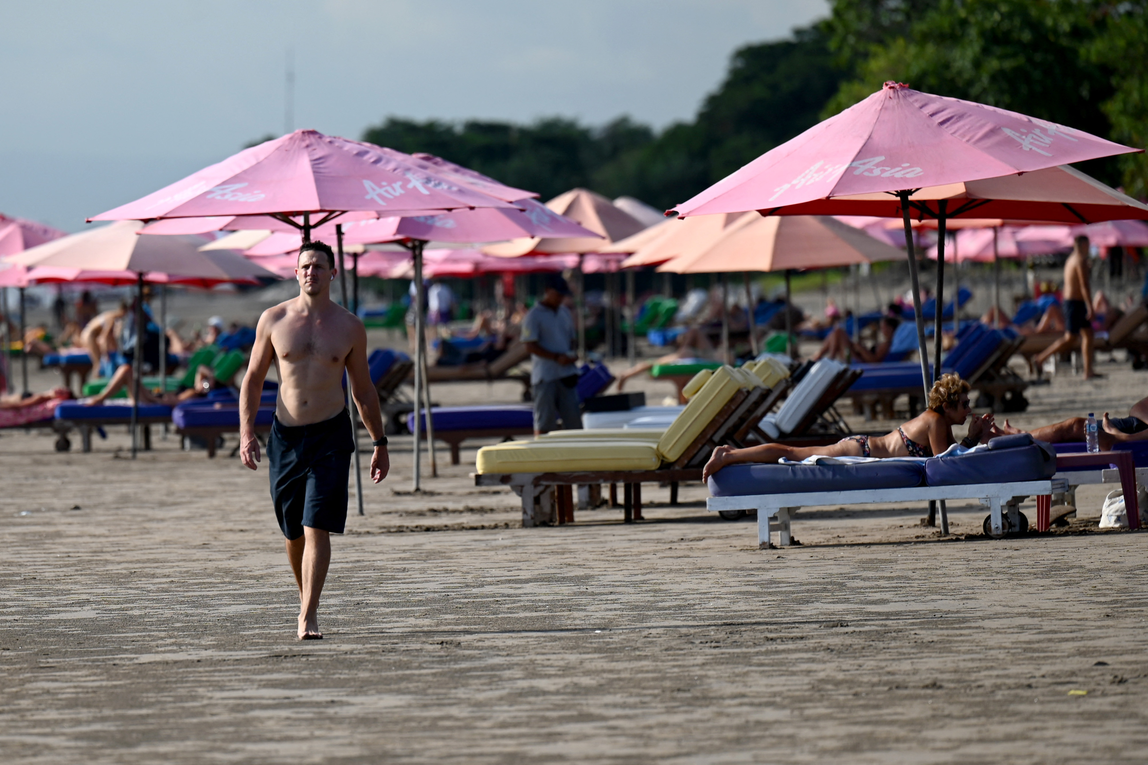A tourist walks on a beach on the Indonesian resort island of Bali.