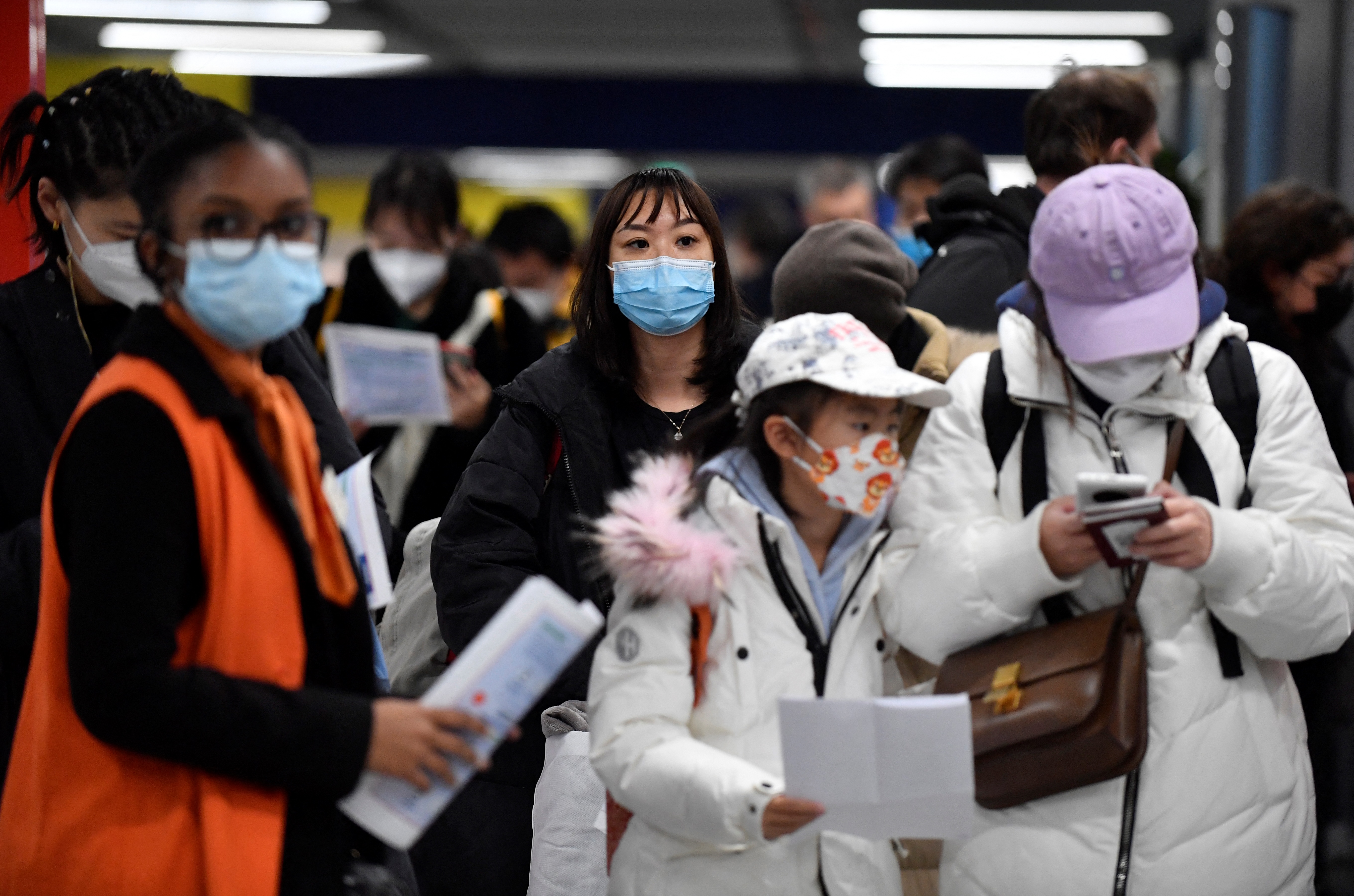 Passengers of a flight from China wait in a line for checking their COVID-19 vaccination documents as a preventive measure against the Covid-19 coronavirus, after arriving at the Paris-Charles-de-Gaulle airport in Roissy, outside Paris